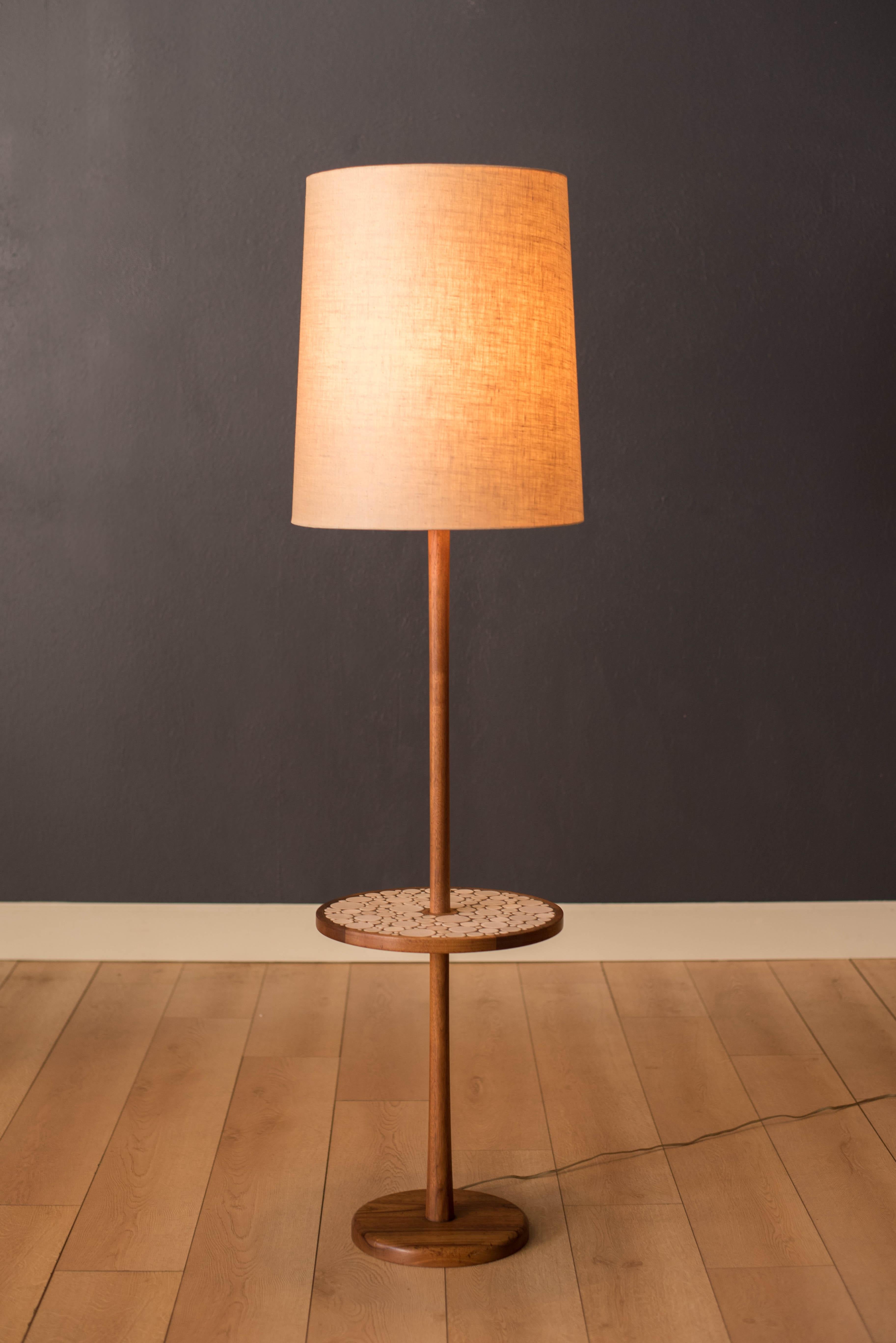 Mid-Century Modern floor lamp with attached round side table designed by Jane and Gordon Martz for Marshall Studios. This versatile piece features a walnut base and unique inlay of ceramic tile including signature Martz details. Lamp shade is not