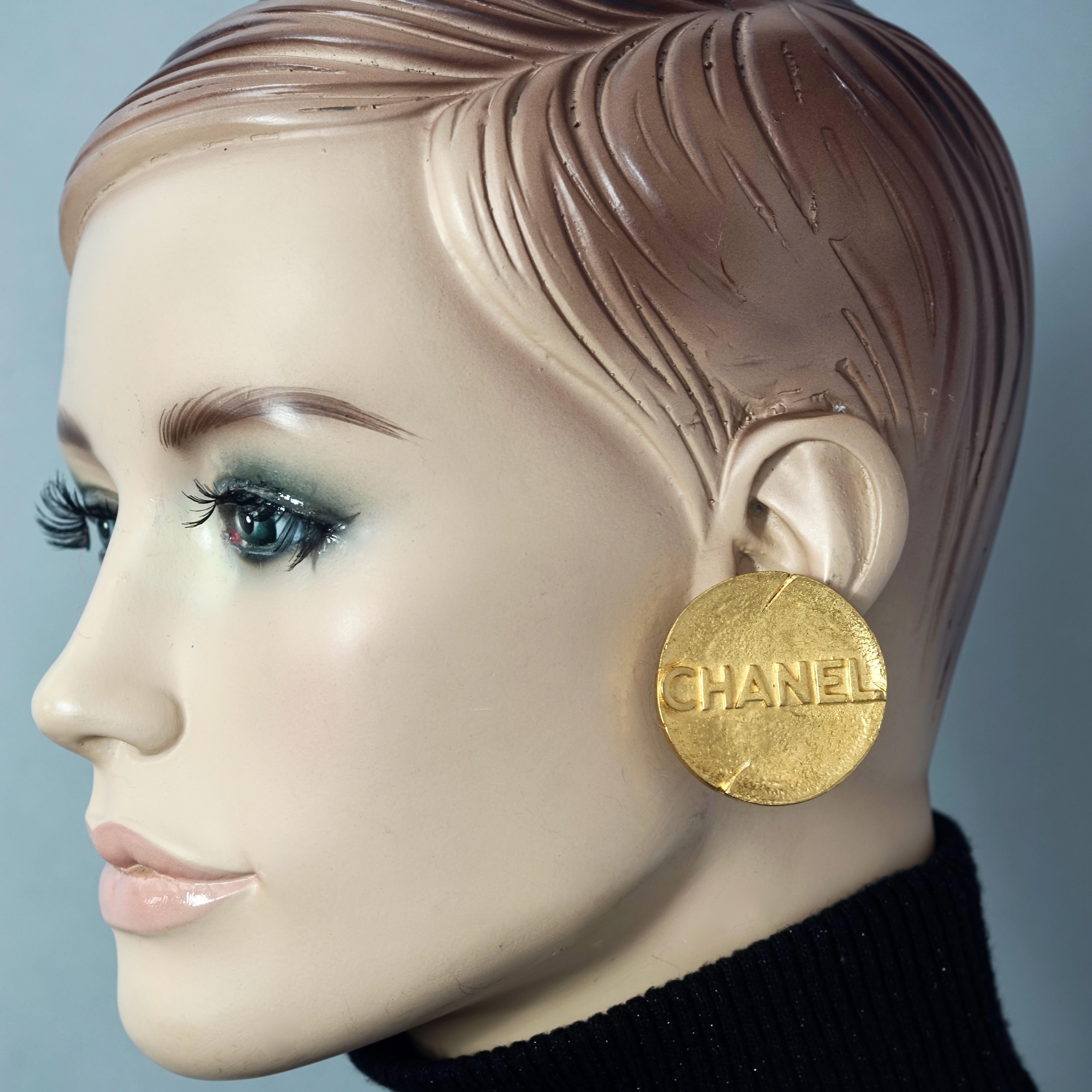 Vintage Massive 1993 CHANEL Spelled Disc Medallion Earrings

Measurements:
Height: 1.57 inches (4 cm)
Width: 1.57 inches (4 cm)
Weight per Earring: 21 grams

Features:
- 100% Authentic CHANEL.
- Massive disc with embossed spelled CHANEL across.
-