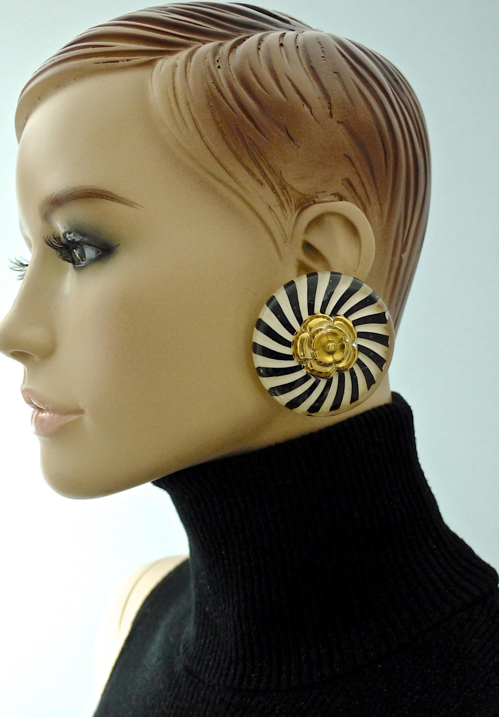 Vintage Massive CHANEL Camellia Stripe Lucite Earrings

Measurements:
Height: 2.16 inches (5.5 cm)
Width: 2.16 inches (5.5 cm)
Weight per Earring: 43 grams

Features:
- 100% Authentic CHANEL.
- Iconic Camellia centrepiece.
- Massive lucite resin