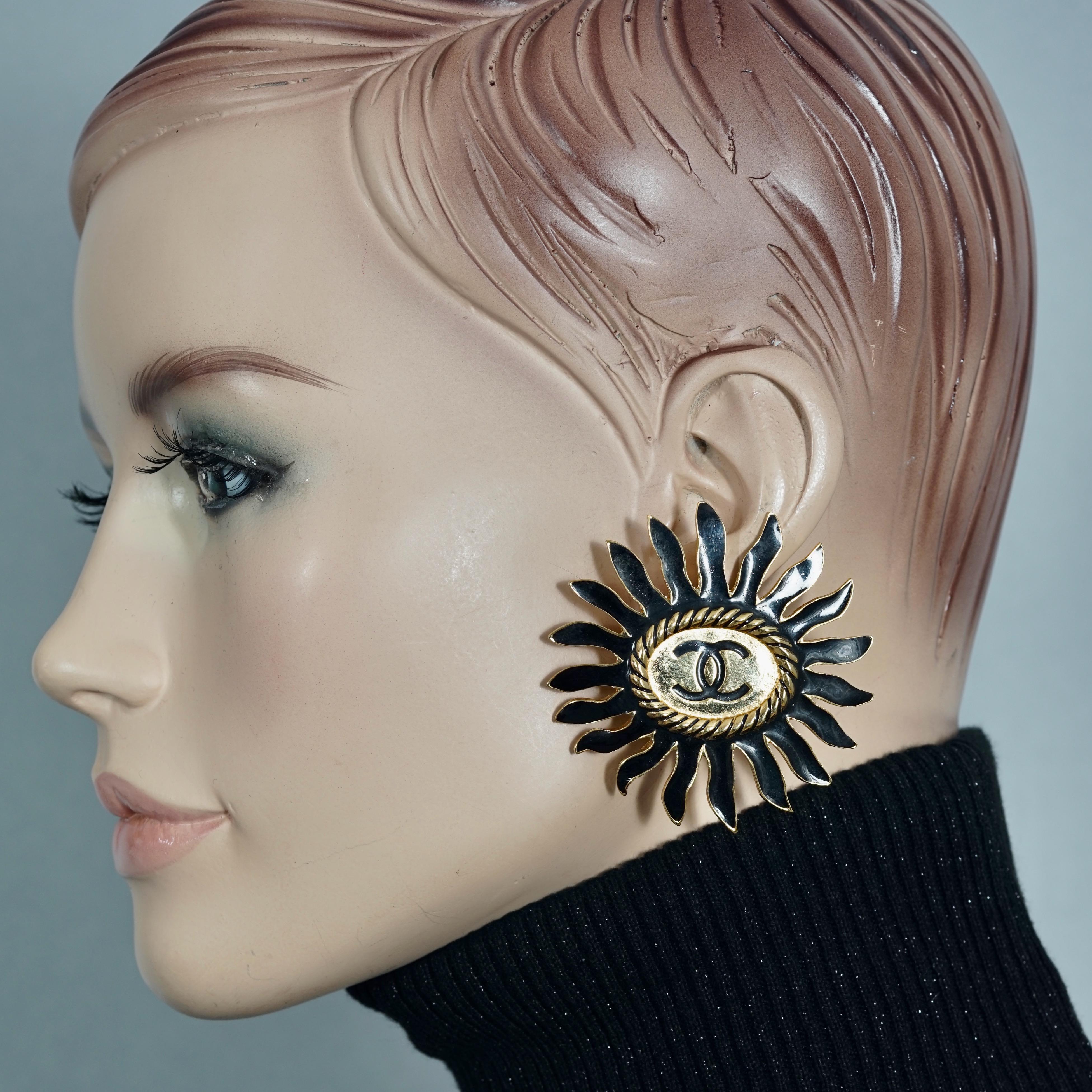 Vintage Massive CHANEL Logo Enamel Flower Earrings

Measurements:
Height: 2.30 inches (5.85 cm)
Width: 2.30 inches (5.85 cm)
Weight per Earring: 29 grams

Features:
- 100% Authentic CHANEL.
- Massive flower with black enamel and CC logo at the