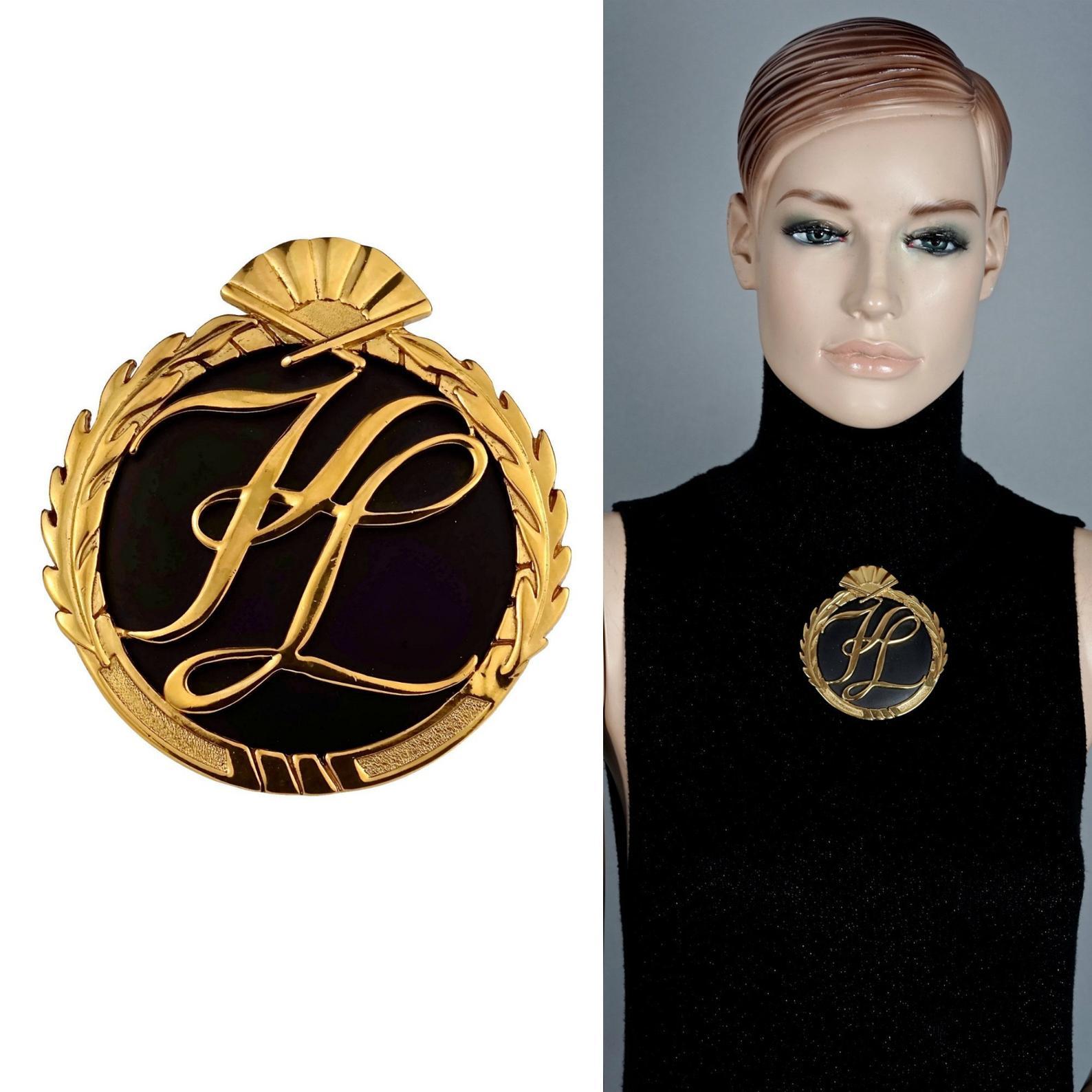 Vintage Massive Iconic KARL LAGERFELD KL Logo Fan Medallion Brooch

Measurements:
Height: 3.38 inches (8.6 cm)
Width: 3.11 inches (7.9 cm)

Features:
- 100% Authentic KARL LAGERFELD.
- Embossed KL initials at the center.
- Ornate leaves and fan