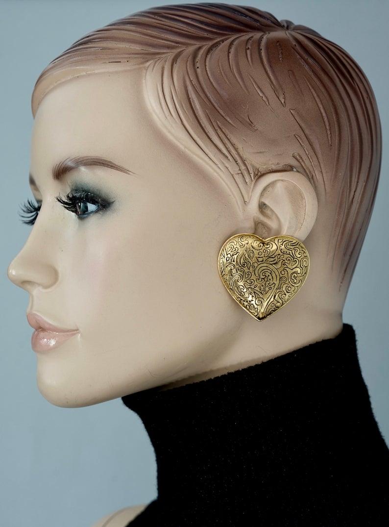 Vintage Massive YVES SAINT LAURENT Ysl Arabesque Heart Earrings

Measurements:
Height: 1.65 inches (4.2 cm)
Width: 1.73 inches (4.4 cm)
Weight: 18 grams

Features:
- 100% Authentic YVES SAINT LAURENT.
- Massive heart in Arabesque pattern.
- Gold