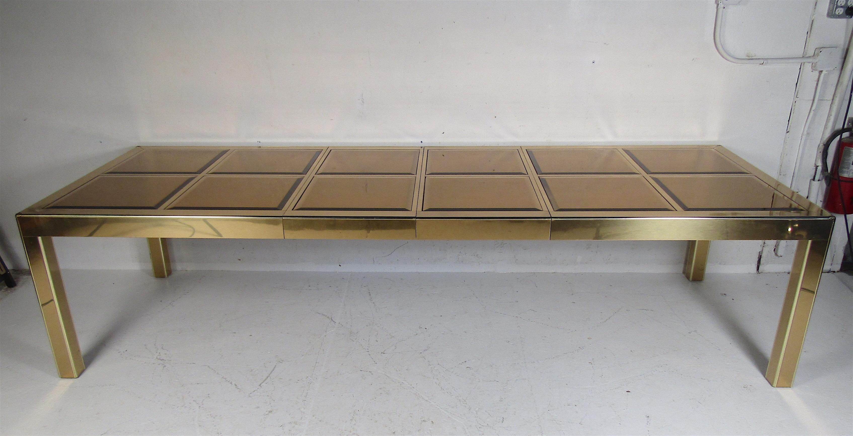 This elegant Mid-Century Modern dining table includes two leaves allowing this to extend from 81 inches wide all the way to 120.5 inches wide. Twelve bronze colored mirror top inserts with beveled edges sit comfortably into their designated