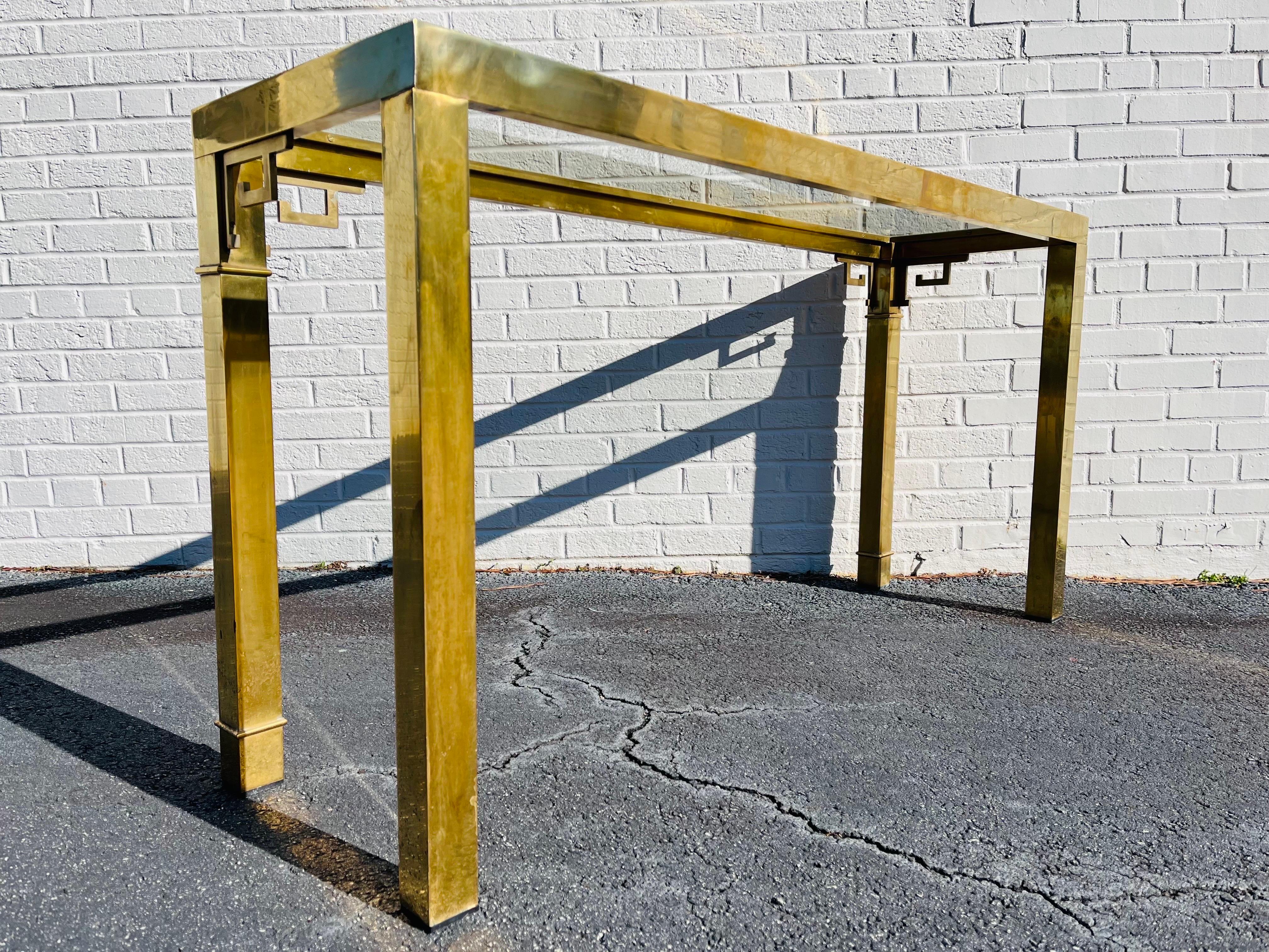 A vintage, 1970's era beautiful brass and glass console table by Mastercraft. The sofa or hall table features banding around the legs as well as Greek Key designs in the front and side corners. The heavyweight brass and strong lines are in perfect