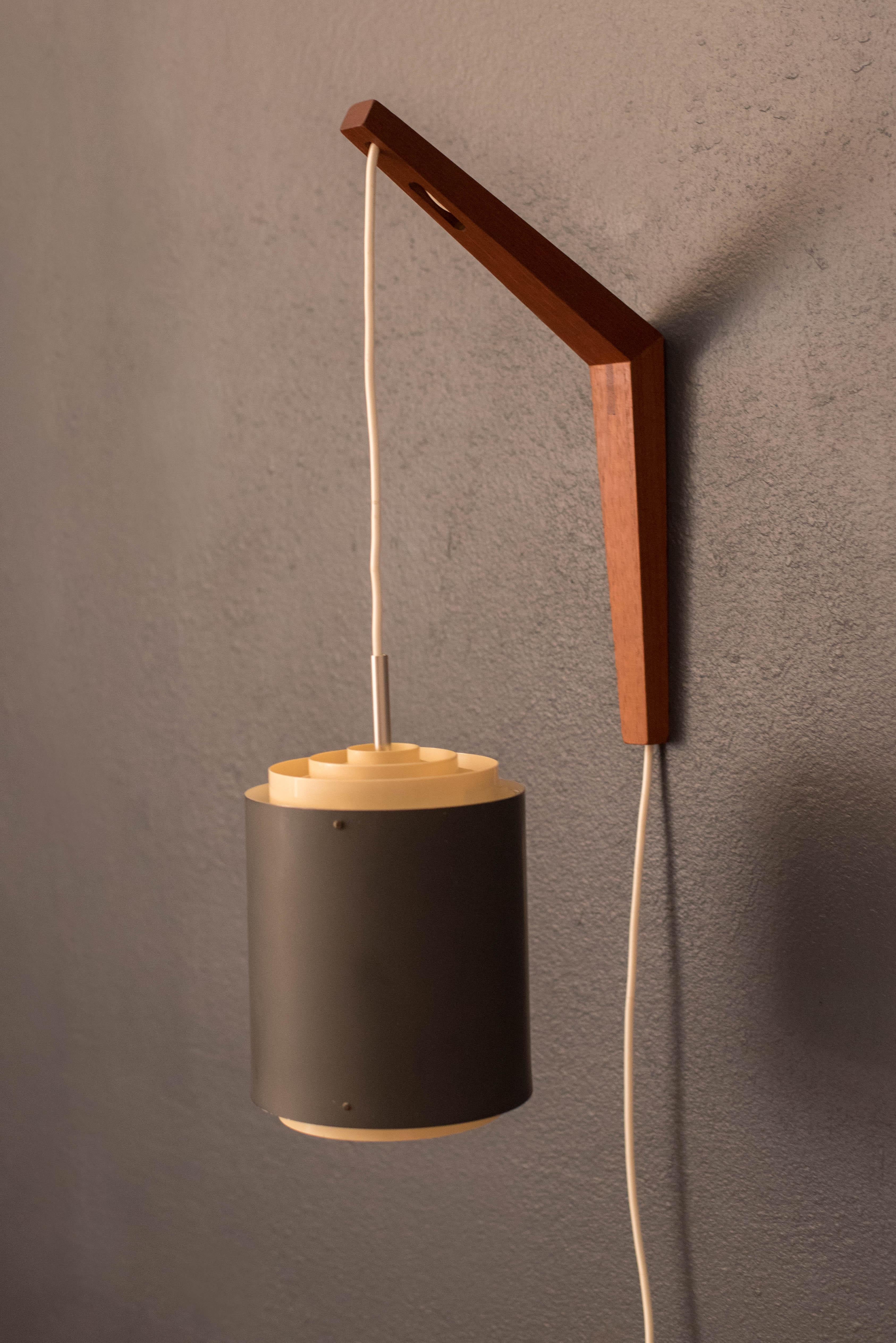 Mid-Century Modern matte blue adjustable hanging pendant lamp and teak wall mount circa 1960's. This piece features a cylinder shade that illuminates a soft light through the top and bottom diffusers. Perfect to use as a reading light or accent