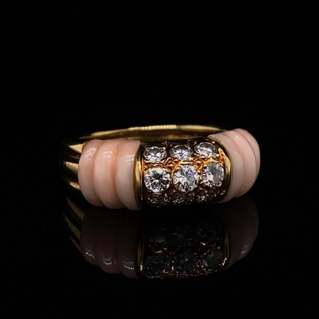 A vintage Mauboussin angel skin coral 18 karat yellow gold diamond ring, circa 1990

Two fine ribbed angel hair coral sections of this elegant ring frame a central yellow gold centre grain set with nine round brilliant cut diamonds of 0.40 carats