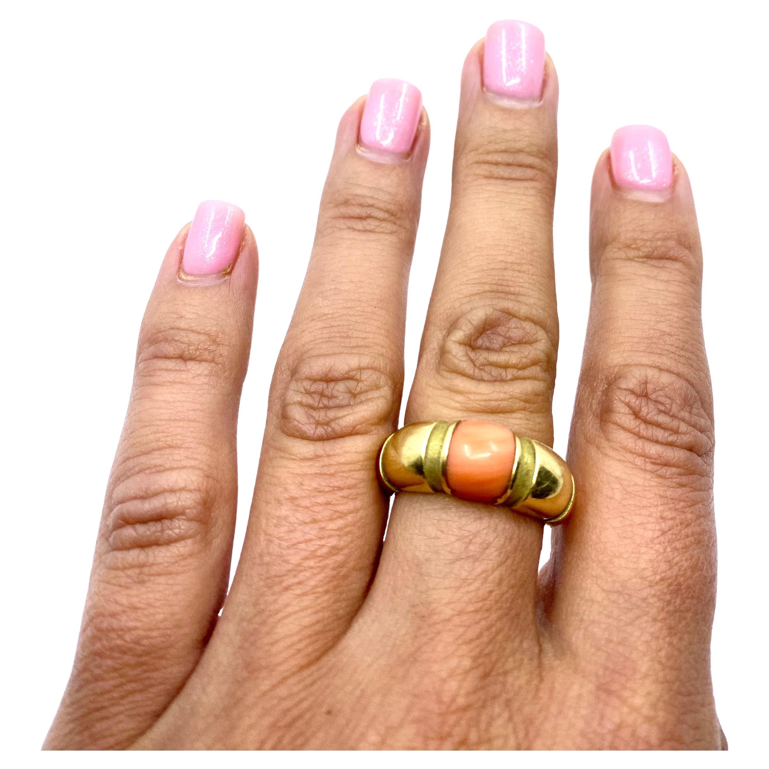 A vintage coral ring by Mauboussin made in 18k gold.
This architectural ring with the cabochon cut coral designed with six vertical   grooves in the band. These grooves are textured, and the band is polished gold. These elements, along with the