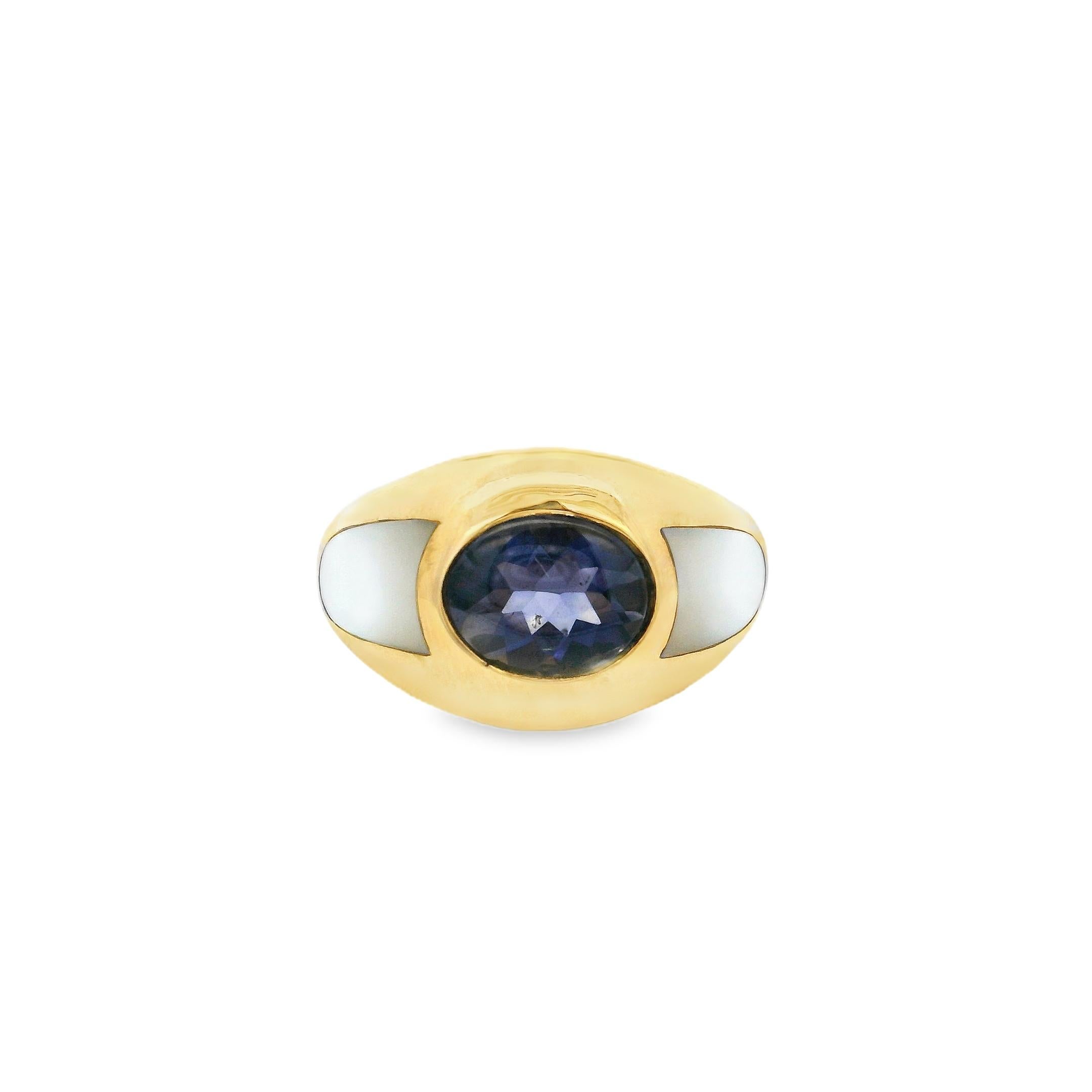 Discover timeless French elegance with this vintage Mauboussin dome ring, crafted in rich 18K yellow gold and set with a deep oval-cut blue iolite at its center. The bold, sculptural form is enhanced by luminous mother-of-pearl inlays on each side,