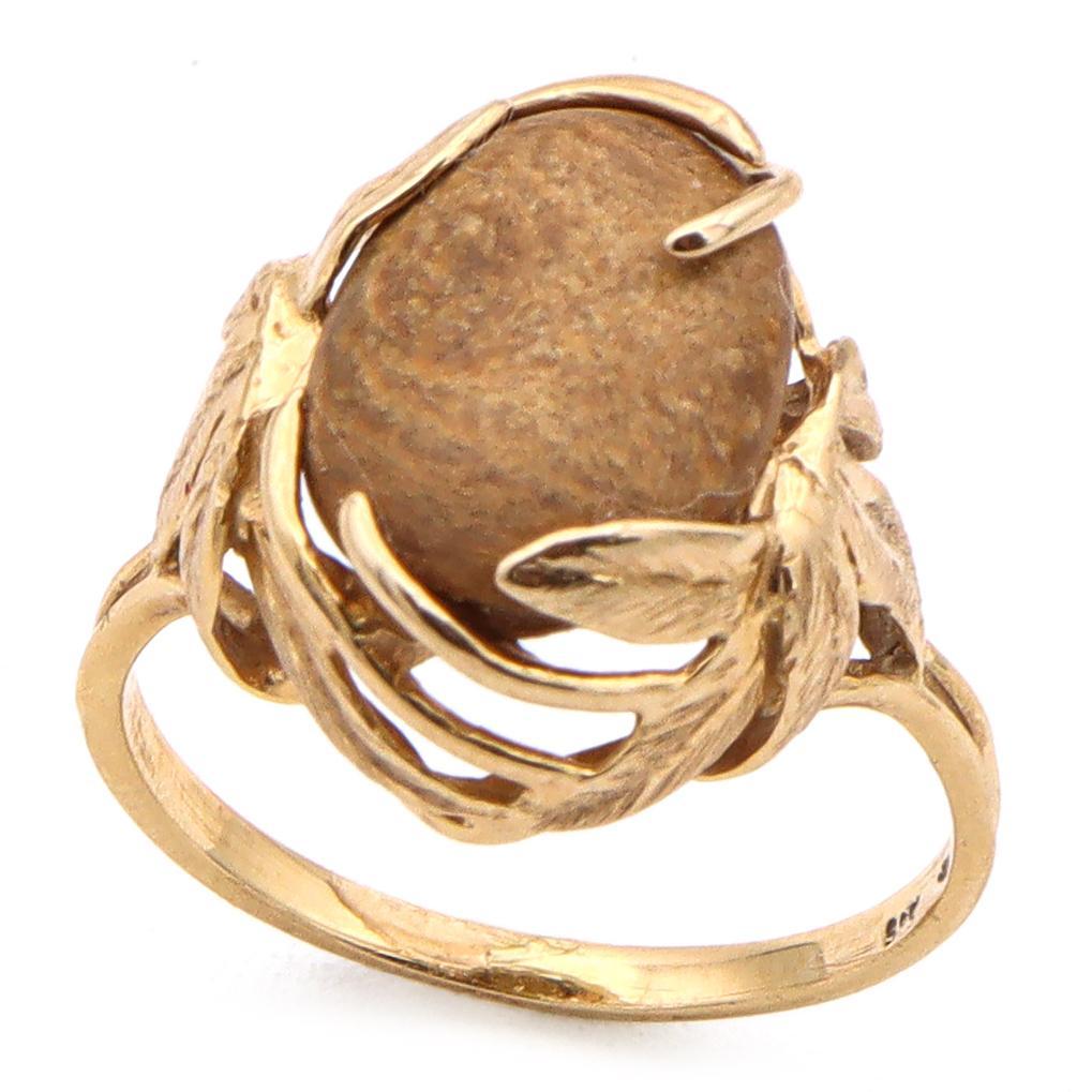 Eine Verschmelzung von Natur und Eleganz. Dieser auffällige Ring zeigt einen glatten, ovalen braunen Korallenstein, der von verschlungenen Blättern aus 14-karätigem Gold umhüllt ist. Das organische Design fließt nahtlos um den zentralen Edelstein