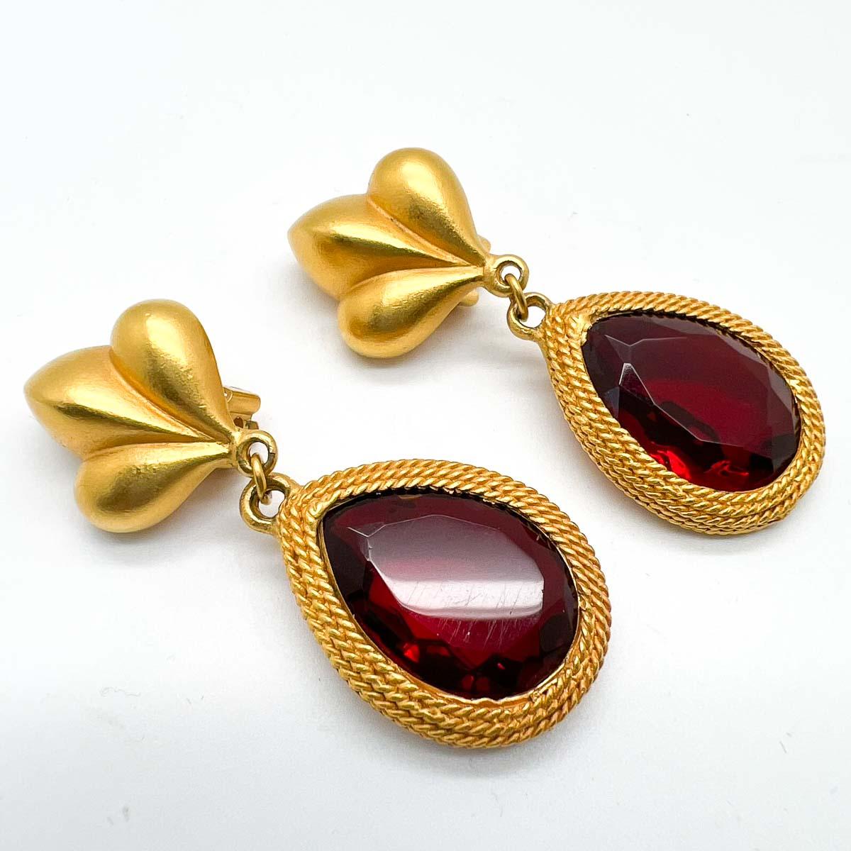 A divine pair of vintage Maxine Denker Ruby Earrings. The brushed gold setting proving a magnificent backdrop for the huge ruby crystal, fancy cut teardrop stone. A vibrant and eternally elegant statement earring from this wonderful New York City