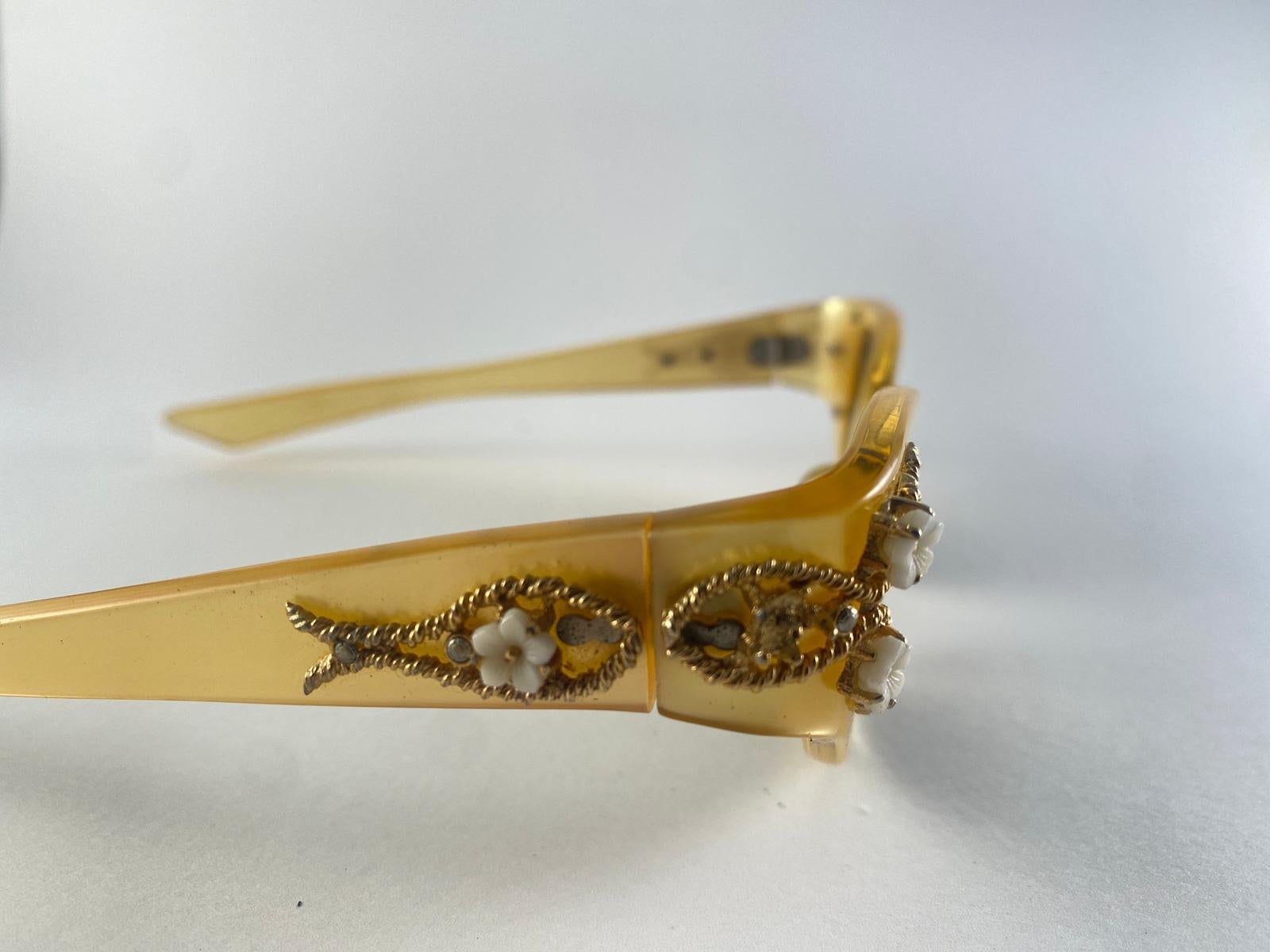Occhiali da sole a occhi di gatto ingioiellati Vintage By May con lenti grigie.

Questo articolo presenta lievi segni di usura sul telaio a causa della conservazione.

Misure 

Parte anteriore : 15,5 cm 
Altezza della lente: 3,7 cm
Larghezza della