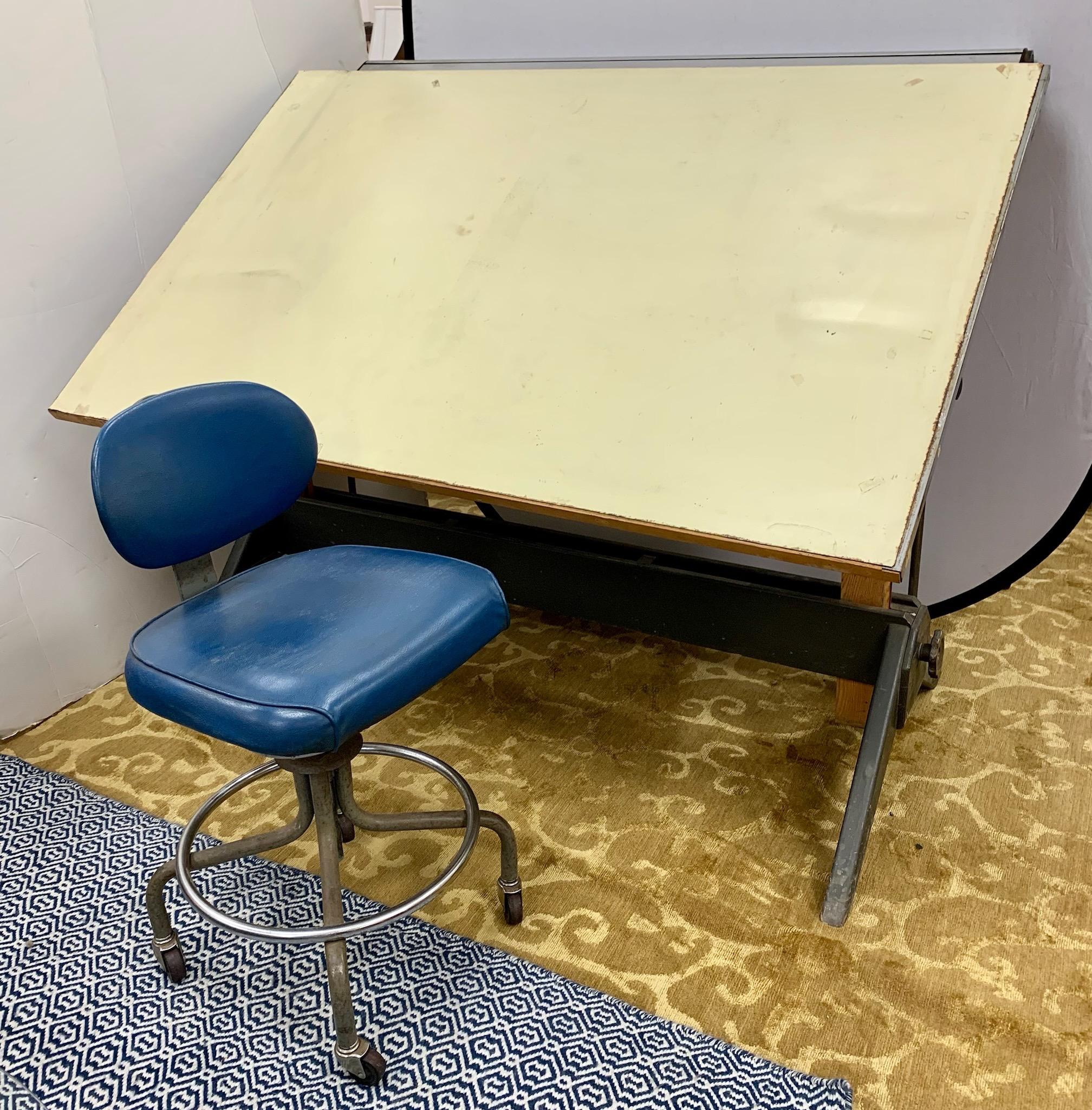 1950's/60's Mid-century architect drafting table. Solid oak with metal base and cast iron hardware. The writing surface under the removable rubber surface has not been examined. With blue leather adjustable swivel chair on castors. Adjustable height