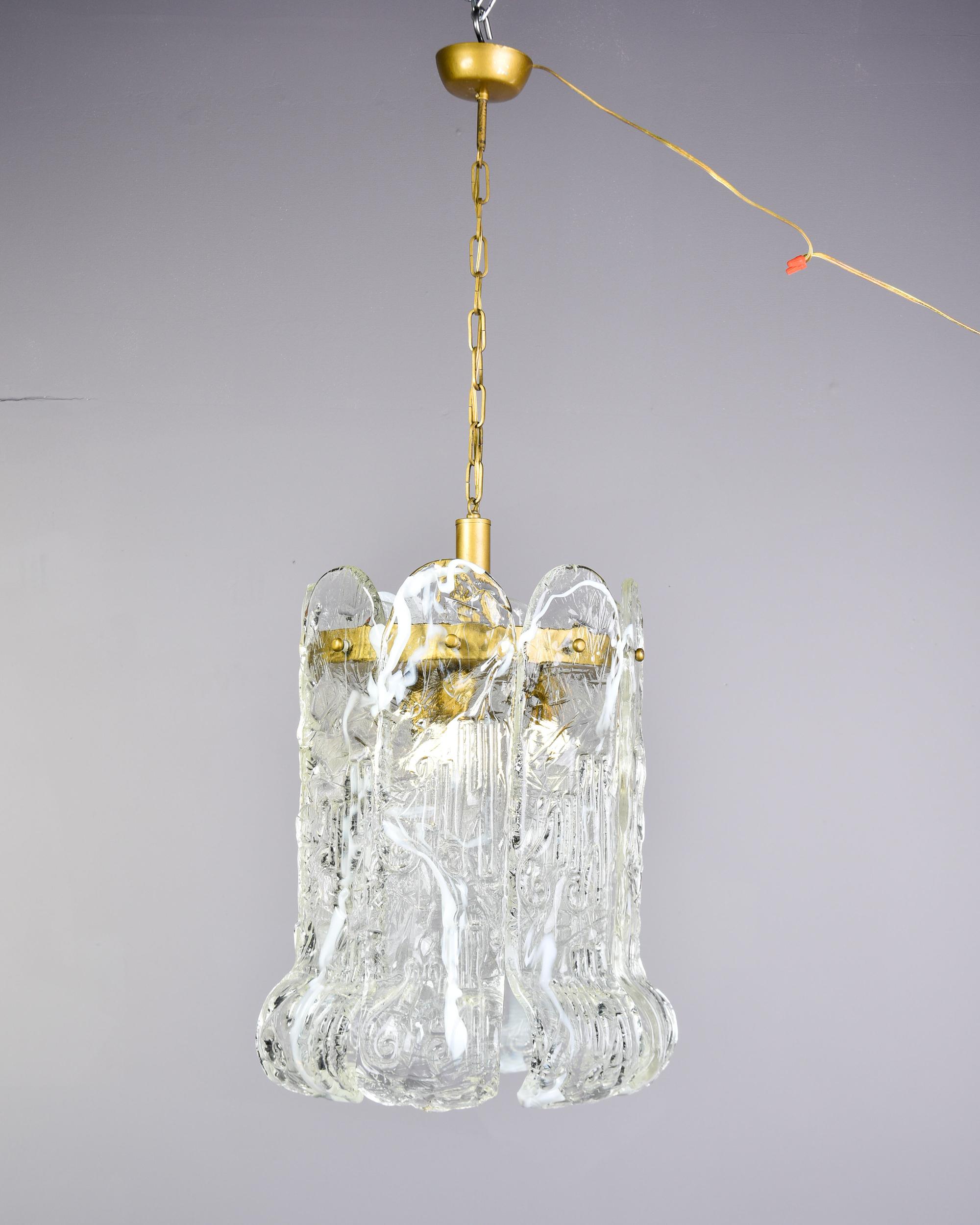 Trouvée en Italie, cette suspension en verre de Murano attribuée à Mazzega date du début des années 1970. Ce luminaire est composé d'un cadre en laiton et de huit grandes pampilles en verre soufflé transparent qui se recourbent aux extrémités. Les