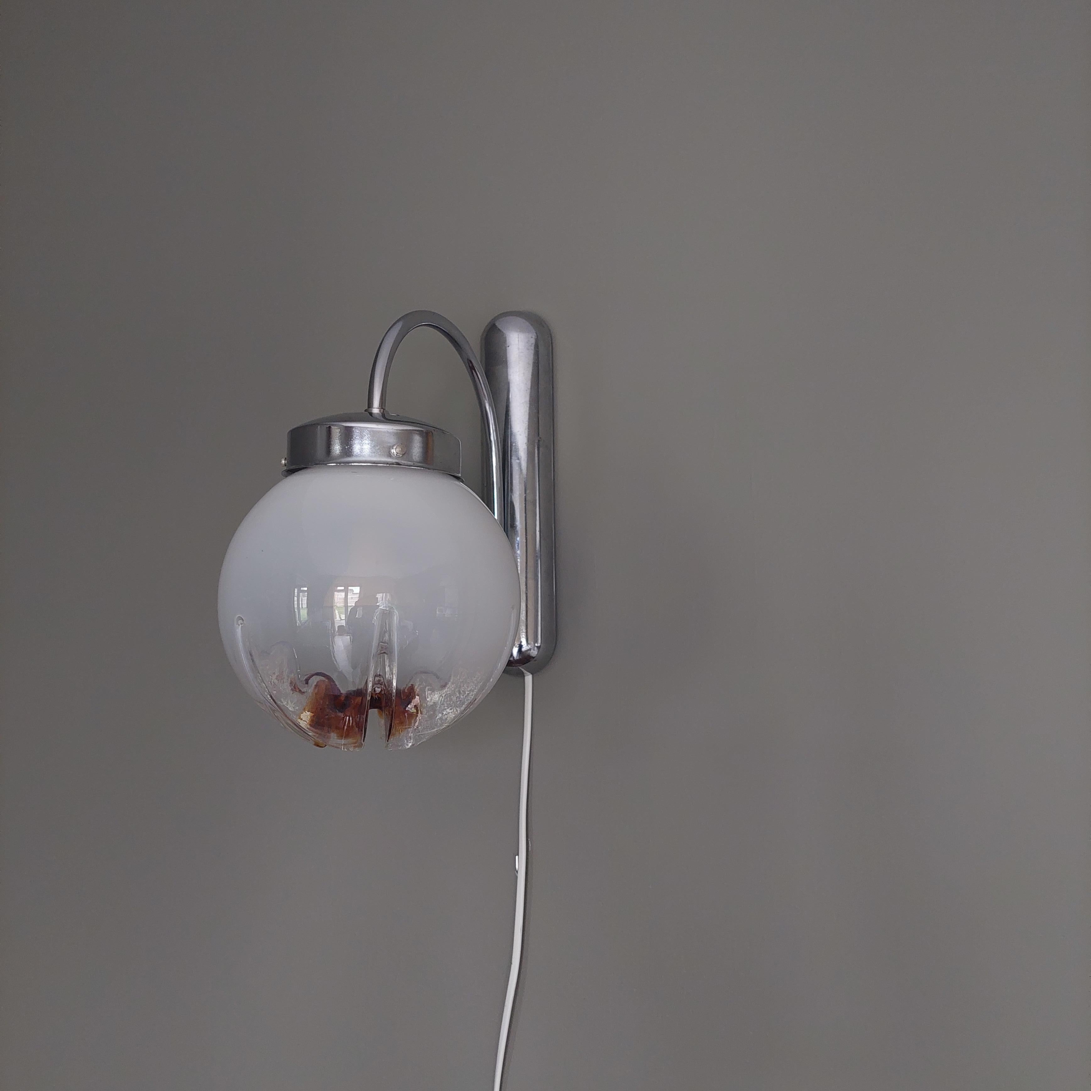 This is a beautiful 70's Mazzega wall light.
The glass globes are typical Toni Zuchieri: Murano glass white to clear gradient with an ochre spot.

The wall attachment and accesories are made of chrome .
The Chrome arm that holds the globe can be