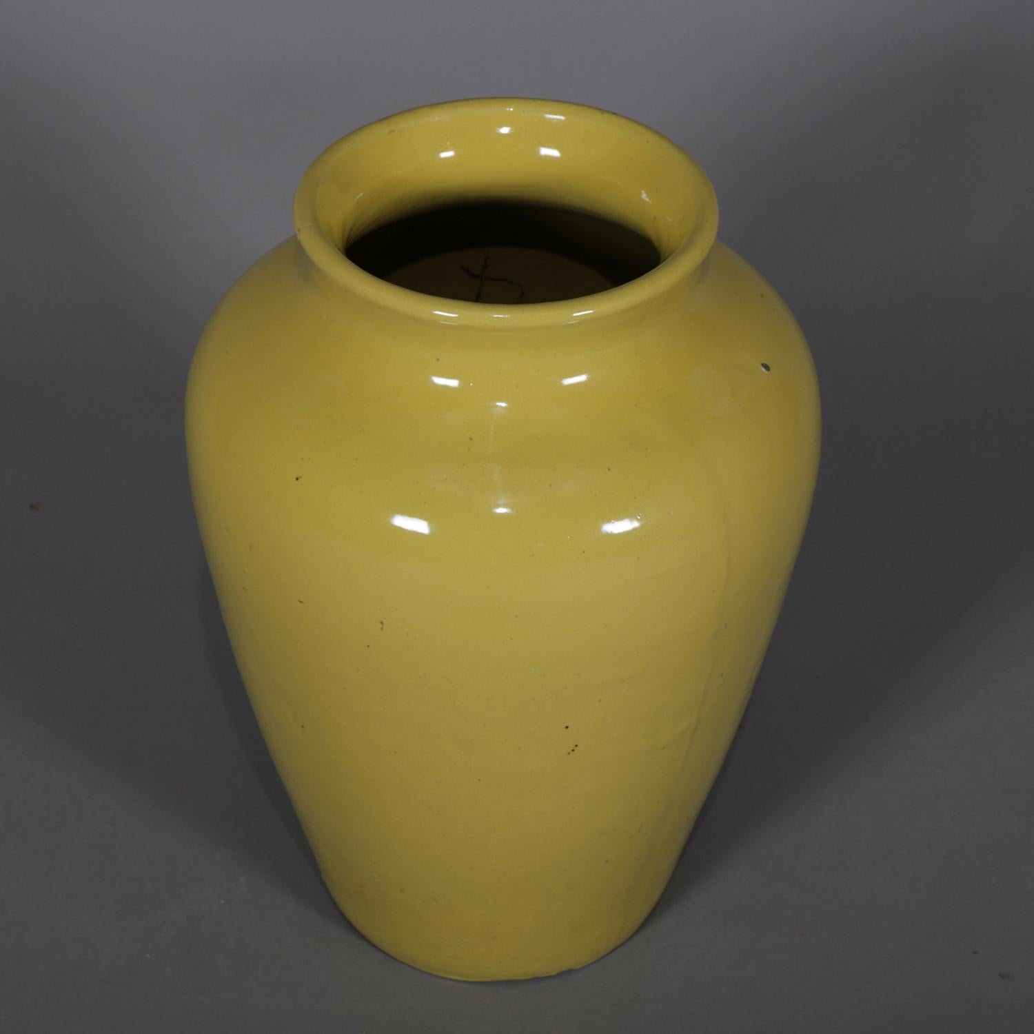 Vintage McCoy school art pottery floor vase features urn form with flared mouth and having yellow glazed exterior, 20th century.

Measures: 18