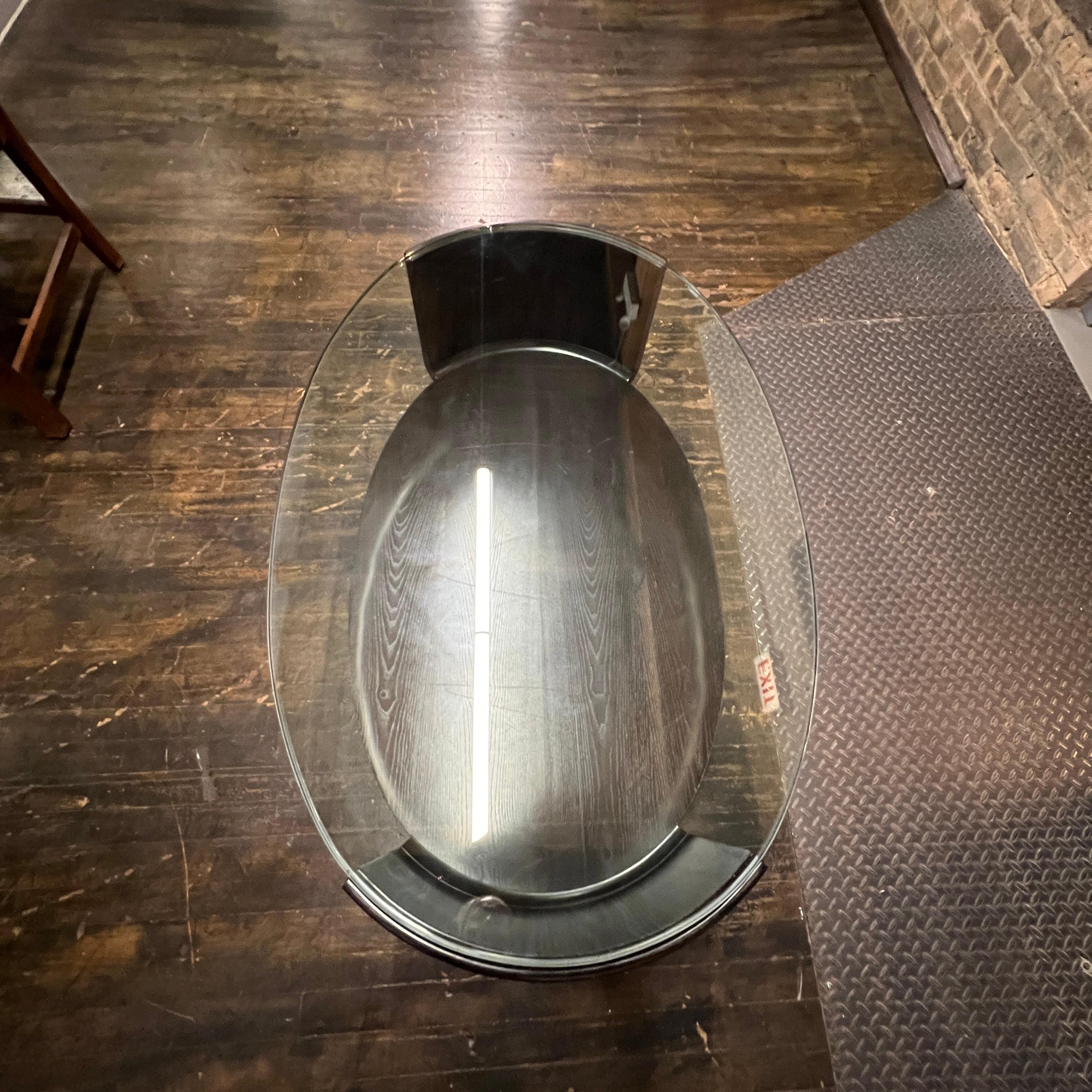 Una preciosa mesa de centro de estilo Art Déco.  Tiene una base ovalada ebonizada con curvas elegantes y una tapa de cristal con inserto de pensamiento.  No estoy seguro del año exacto en que se fabricó, pero los anteriores propietarios pensaban que