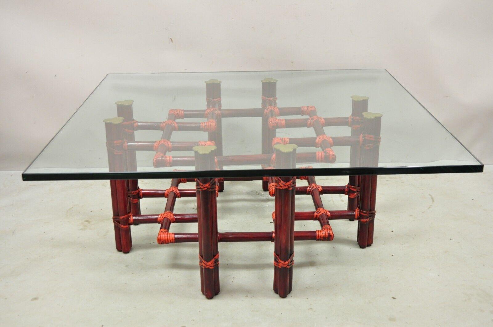 Vintage McGuire Red Rattan Bamboo and Brass Glass Top Square Coffee Table. Item features a thick clear glass top, red finish, brass accents, original label. Circa Late 20th Century. Measurements: 17