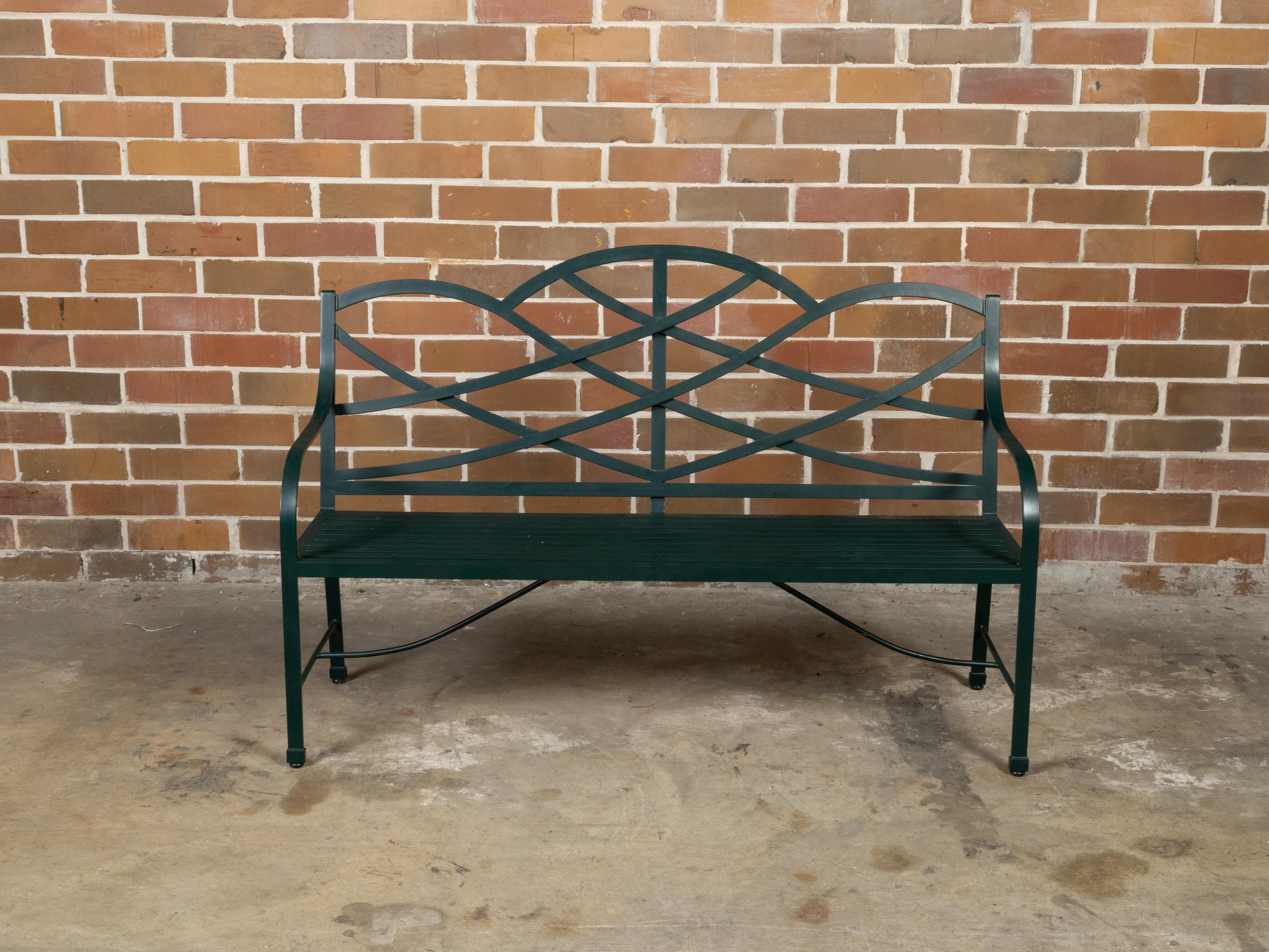 A vintage McKinnon and Harris dark green painted aluminum garden bench from the late 20th century with latticed back, slatted seat and arching top. Made in the USA during the last part of the 20th century, this McKinnon and Harris bench captures our