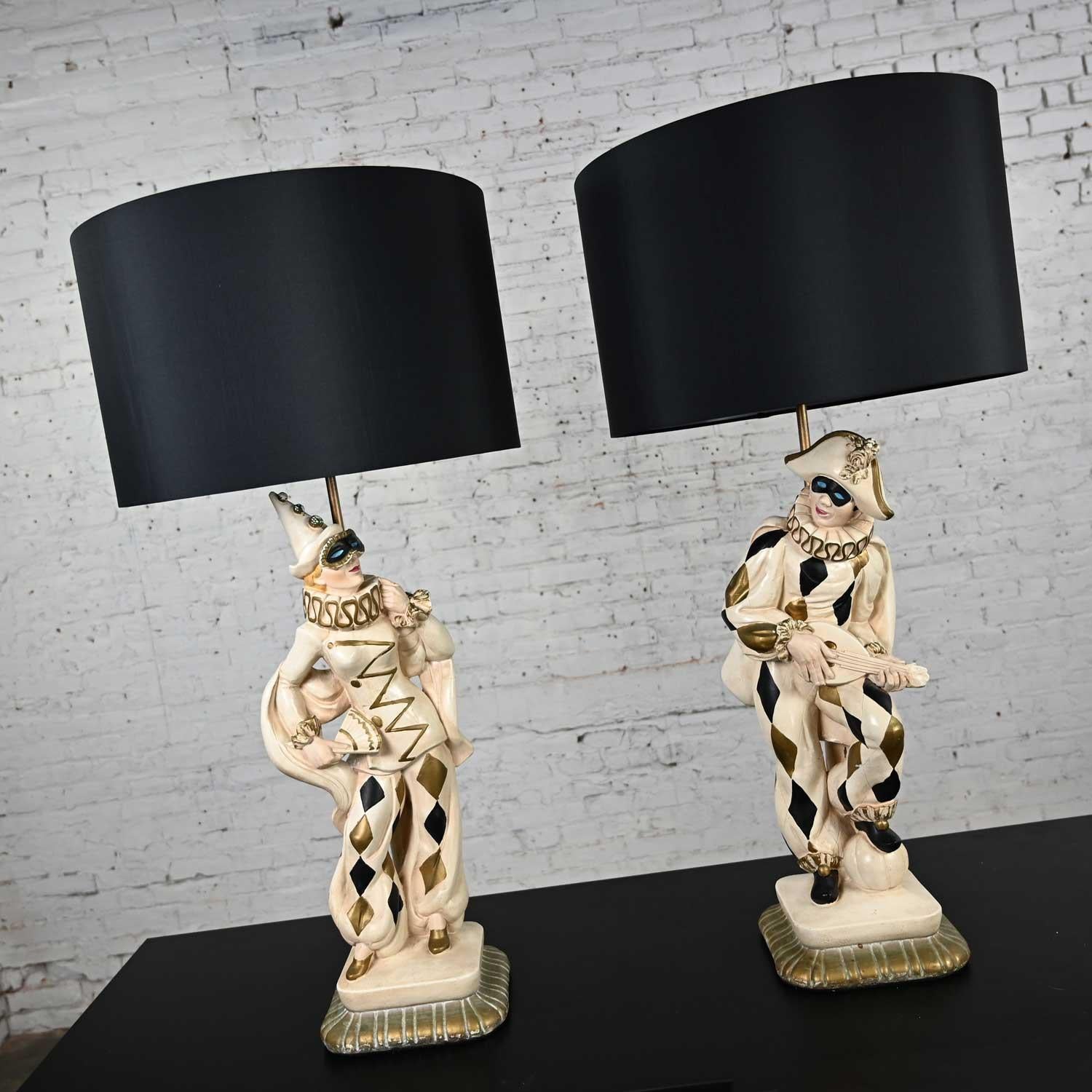 Enjoyable vintage MCM (Mid-Century Modern) Art Deco figural jester or harlequin table lamps in the style of Marbro, a pair. Comprised of molded plaster, hand painted details, antiqued gold painted stems and finials, and new black silk like drum