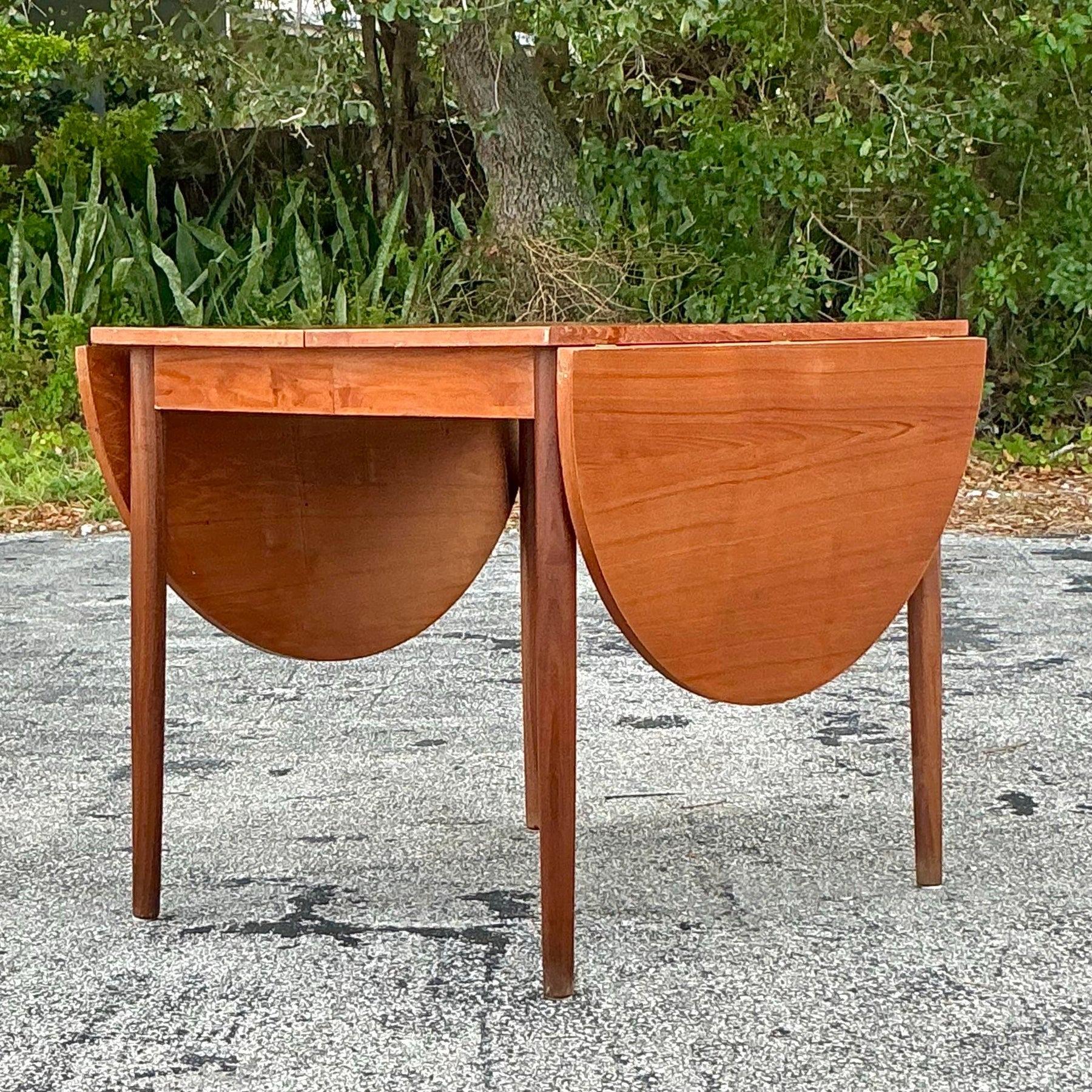 Table de salle à manger extensible Vintage Mid-Century Modern. Dotée de lignes épurées et d'un design polyvalent, cette table se transforme sans problème d'une pièce compacte à une surface de salle à manger spacieuse. Fabriqué dans des tons de bois