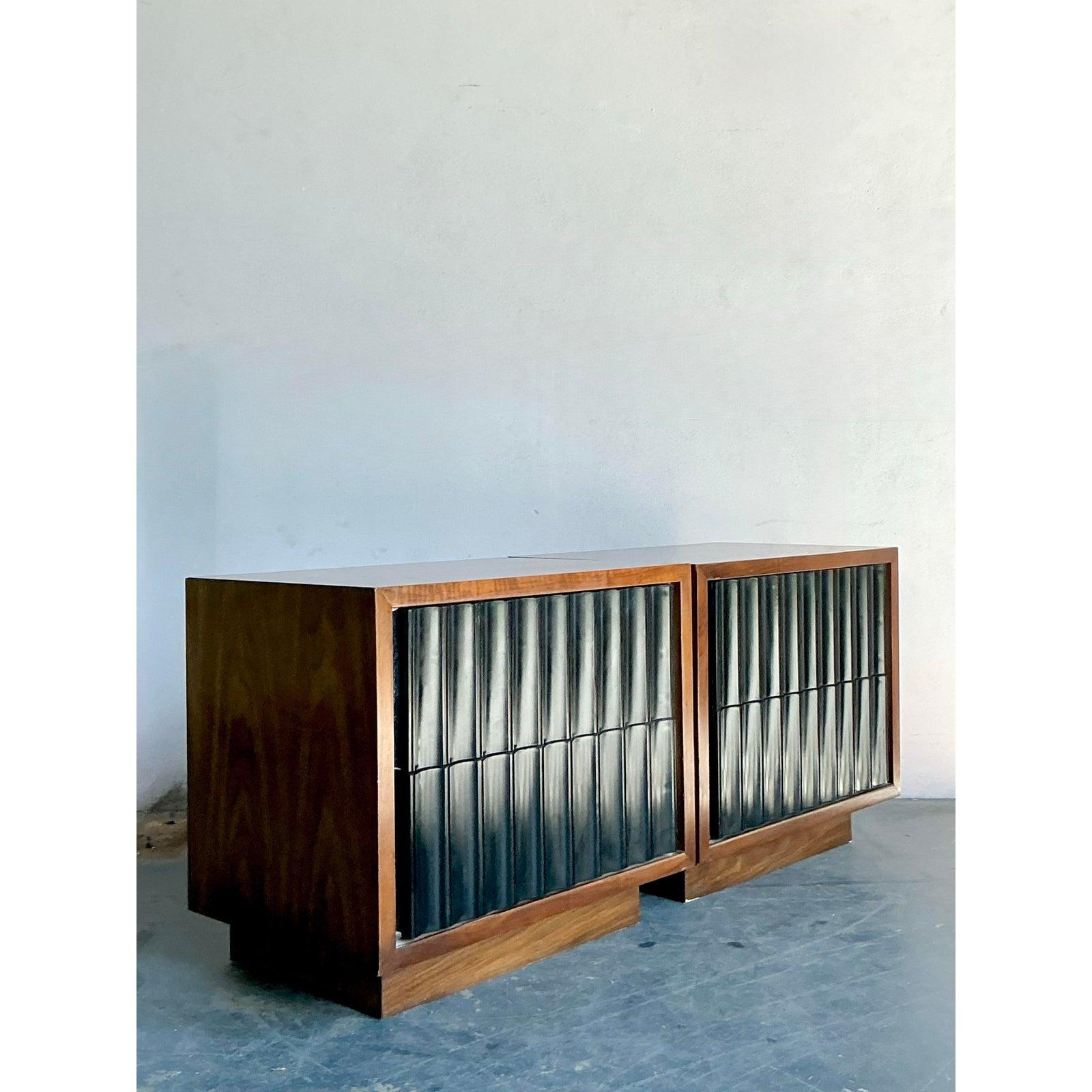 Questa sofisticata coppia di comodini esemplifica il design di qualità del Mid-Century Modern, caratterizzato da integrità strutturale e consistenza visiva. Ogni mobile è caratterizzato da un'impiallacciatura in noce, calda e lucidissima, che crea