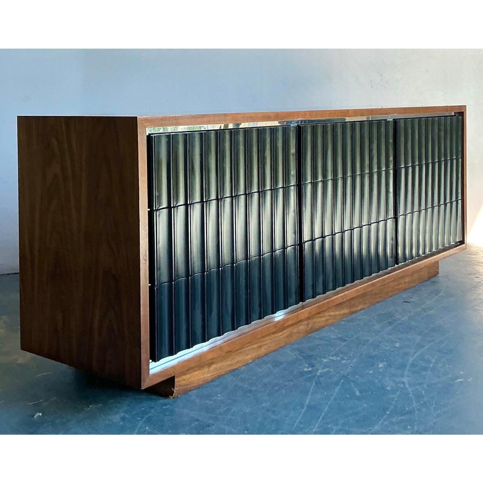 Questa eccezionale credenza è un segno distintivo del sofisticato design del Mid-Century Modern, che incarna l'impegno dell'epoca per le linee pulite, l'eleganza strutturale e la bellezza funzionale. Realizzato in impiallacciatura di noce dai toni
