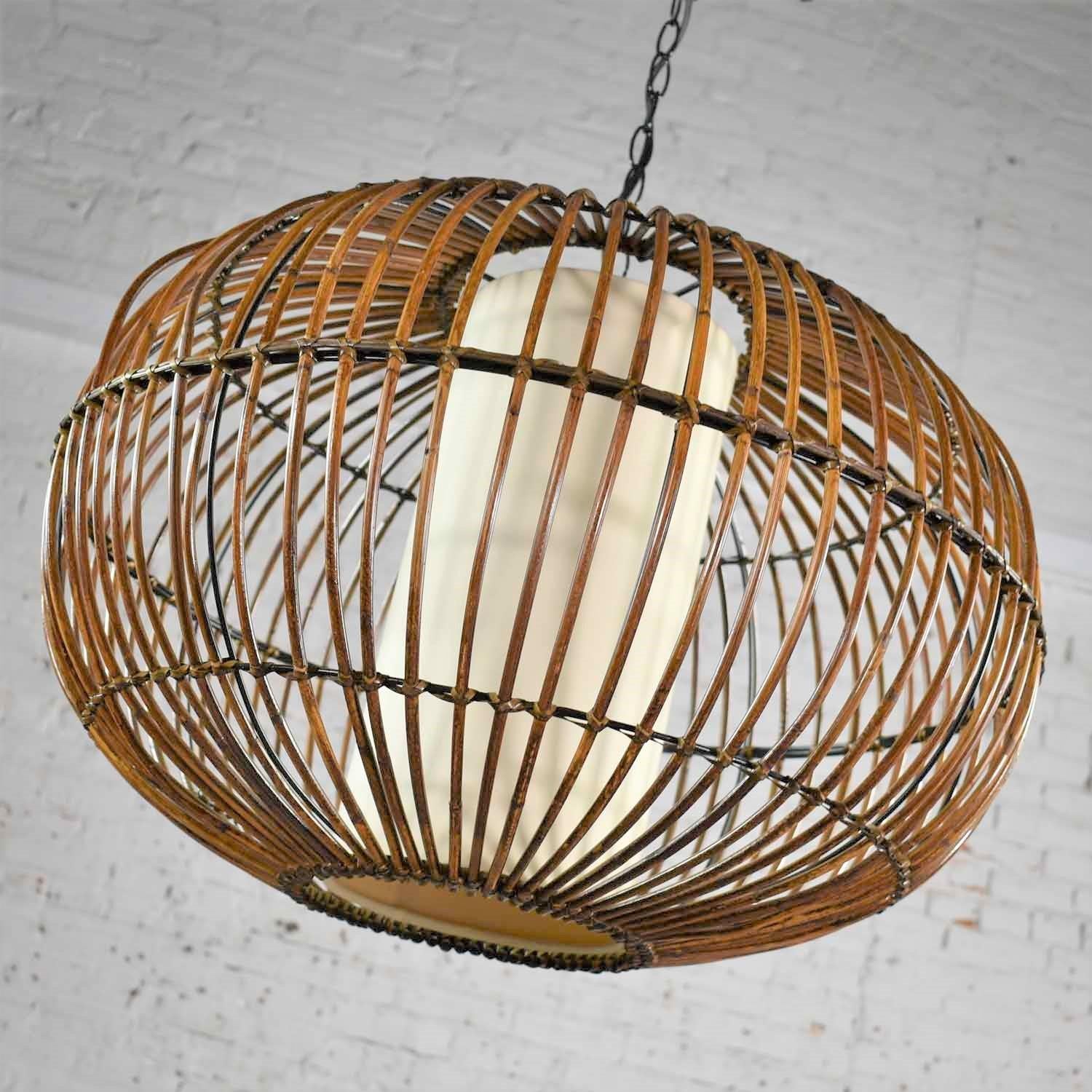 Handsome vintage MCM, Mid-Century Modern, rattan bird cage style pendant chandelier with interior drum shade after Franco Albini. It is in fabulous vintage condition with normal age appropriate wear. There is some wrinkling to the interior drum