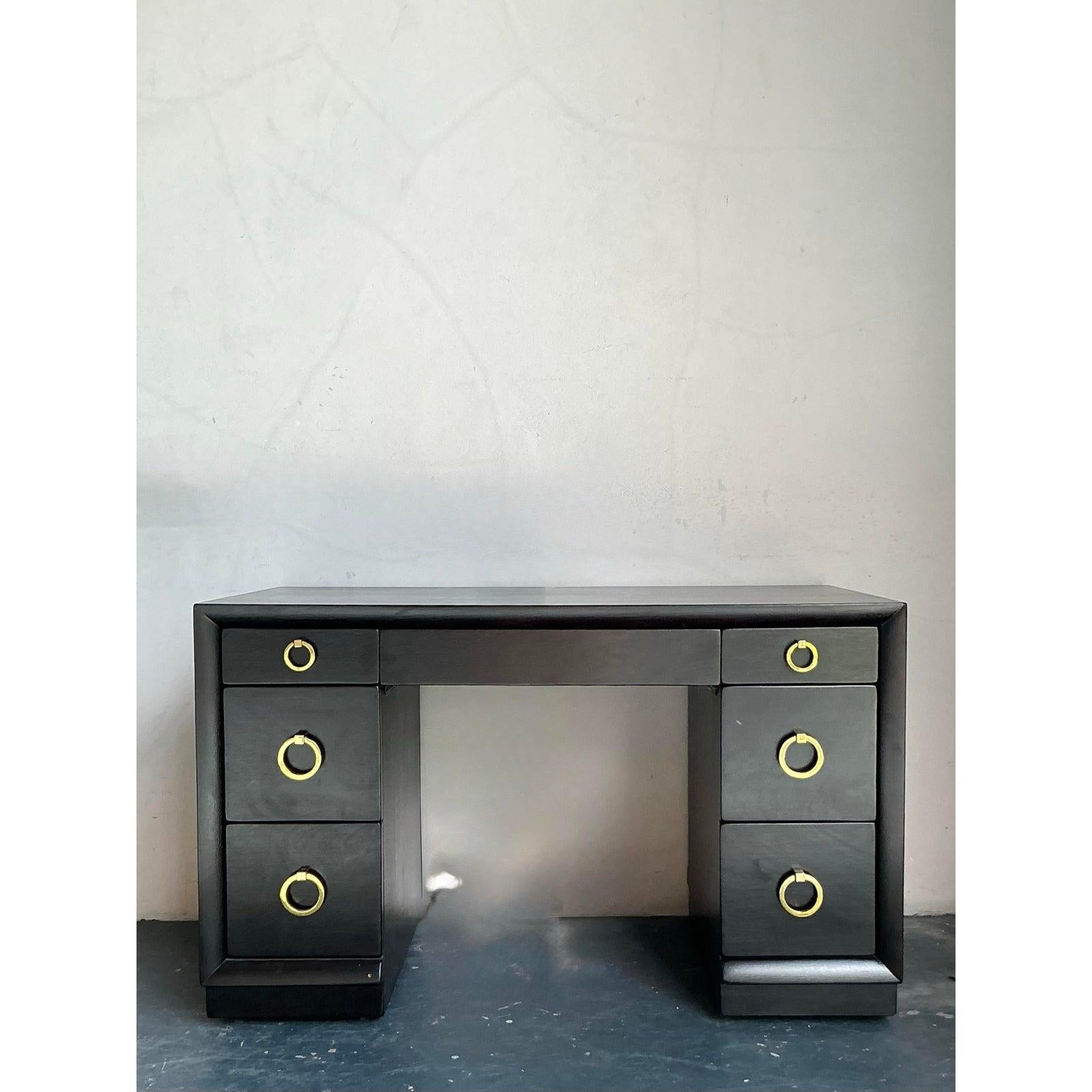 Ti presentiamo un'elegante scrivania d'epoca, testimonianza dell'iconico design di H. H. Robsjohn-Gibbings per Widdicomb. Questo capolavoro del Mid-Century Modern mette in mostra il caratteristico mix di proporzioni classiche e semplicità
