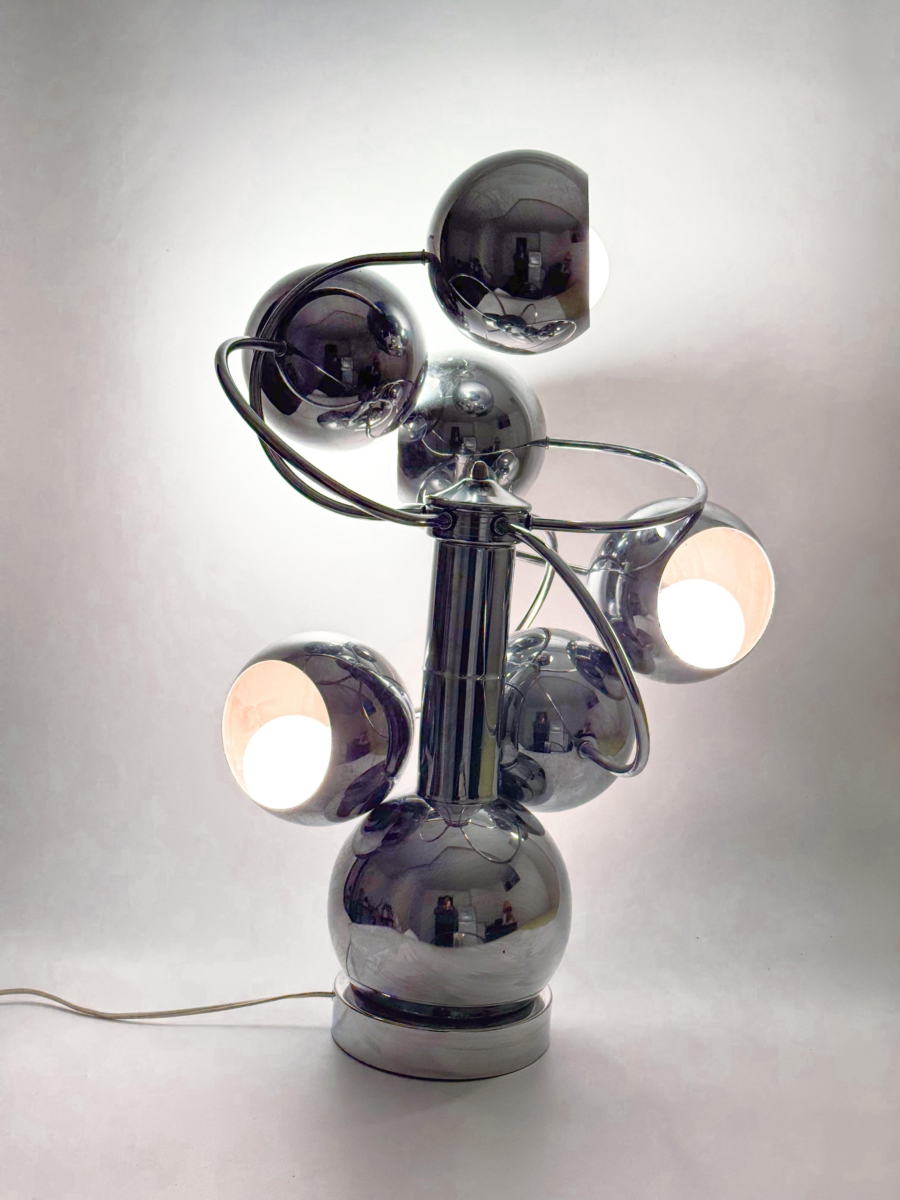 A striking Mid-Century Modern Space Age table lamp featuring six chrome eyeball orbs arranged in a dynamic spiral design. This atomic-era statement piece exemplifies the futuristic design language of the late 1960s to early 1970s, inspired by the