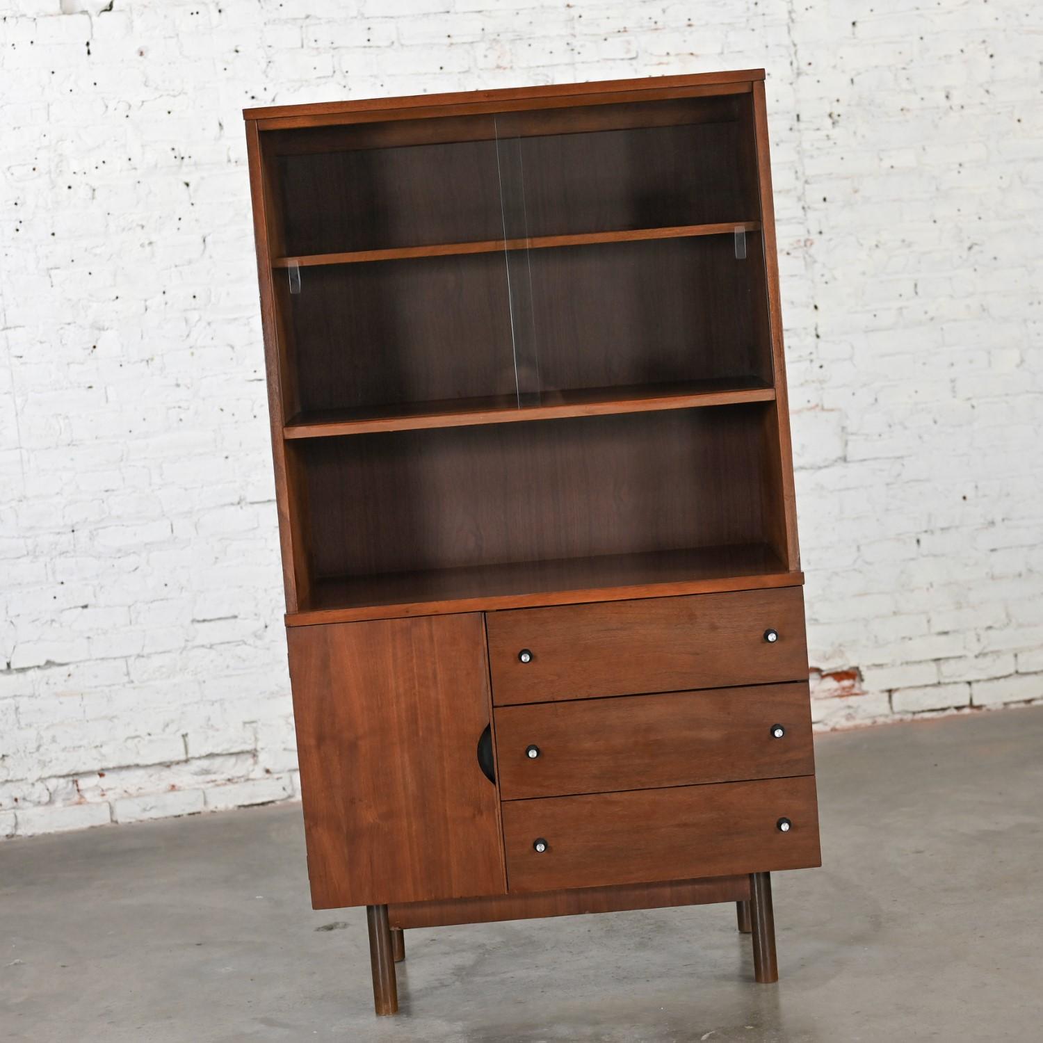 Spectacular Mid-20th Century Mid Century Modern Stanley Furniture petite walnut China cabinet, book or display case comprised of a walnut frame with original natural finish, recessed base, and grooved faux plank sides, sliding glass bypass doors