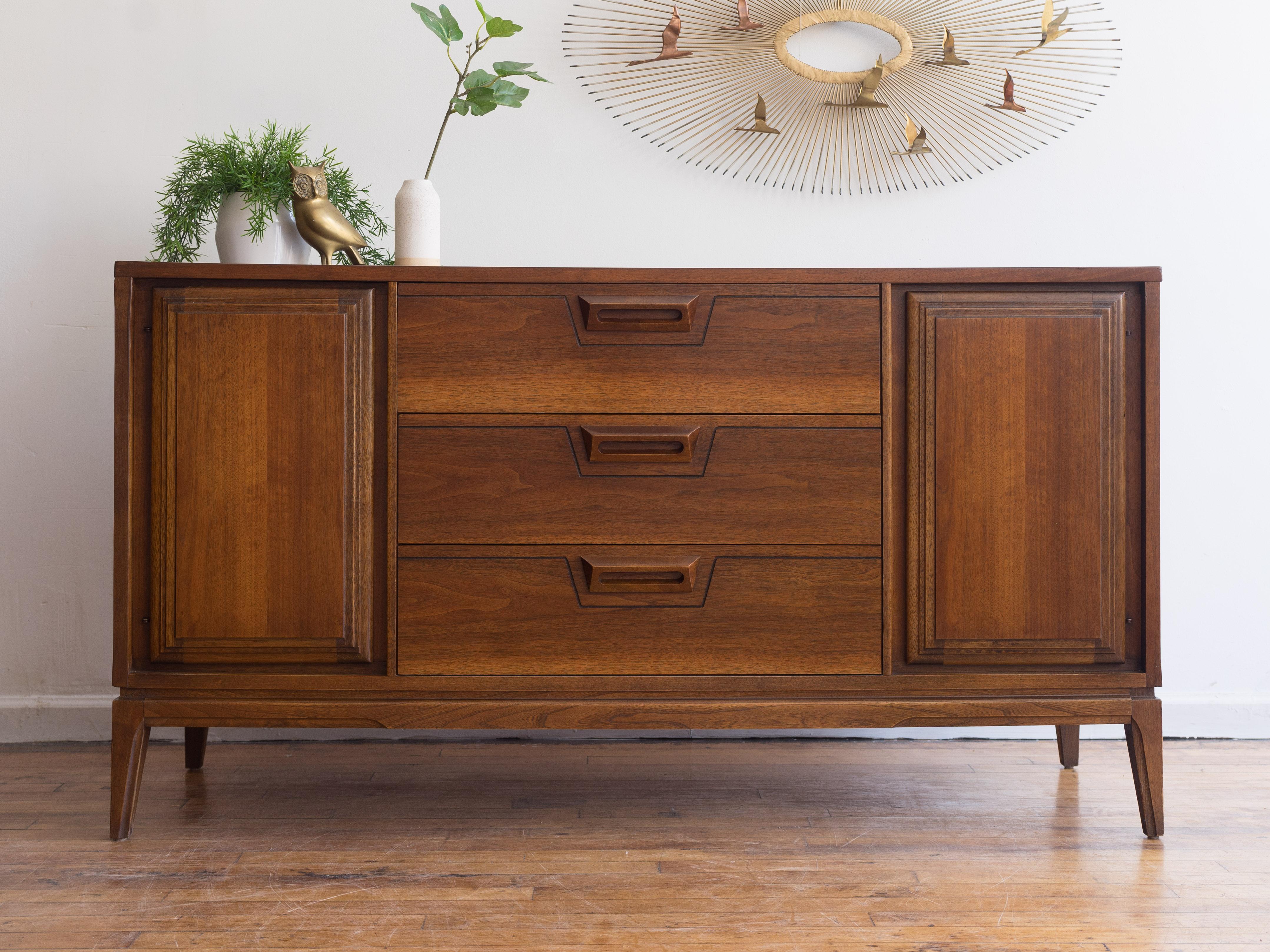 50” x 18” x 31”H

Classic, petite mid-century credenza. 

•walnut throughout
•three drawers
•two doors hide open storage with a half shelf
•angled walnut pulls

 This is in good vintage condition. There is  minor swelling on the bottom of the right