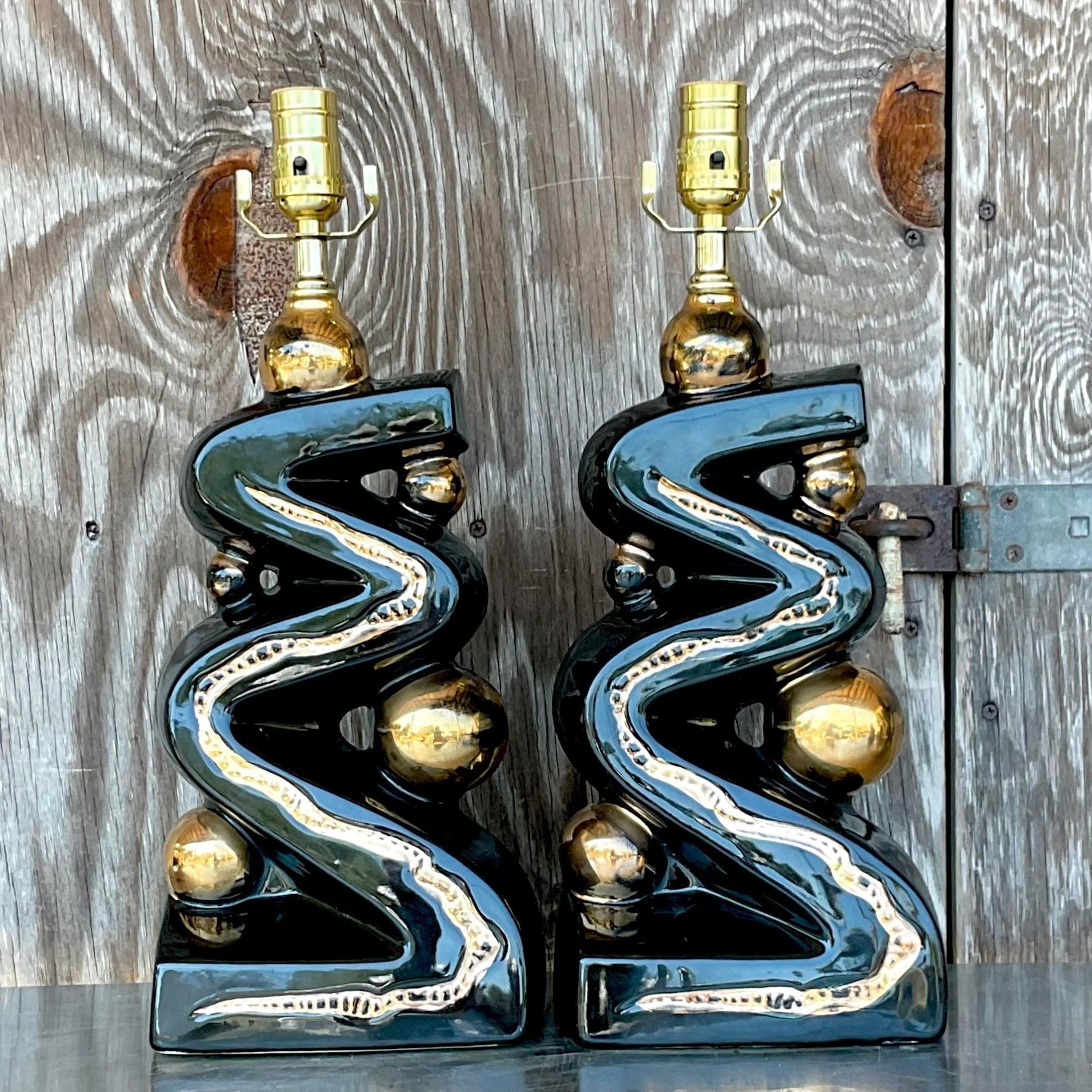 A striking pair of vintage MCM table lamps. A chic zig zag design in glamorous black and gold. Fully restored with all new hardware and wiring. Acquired from a Palm Beach estate.