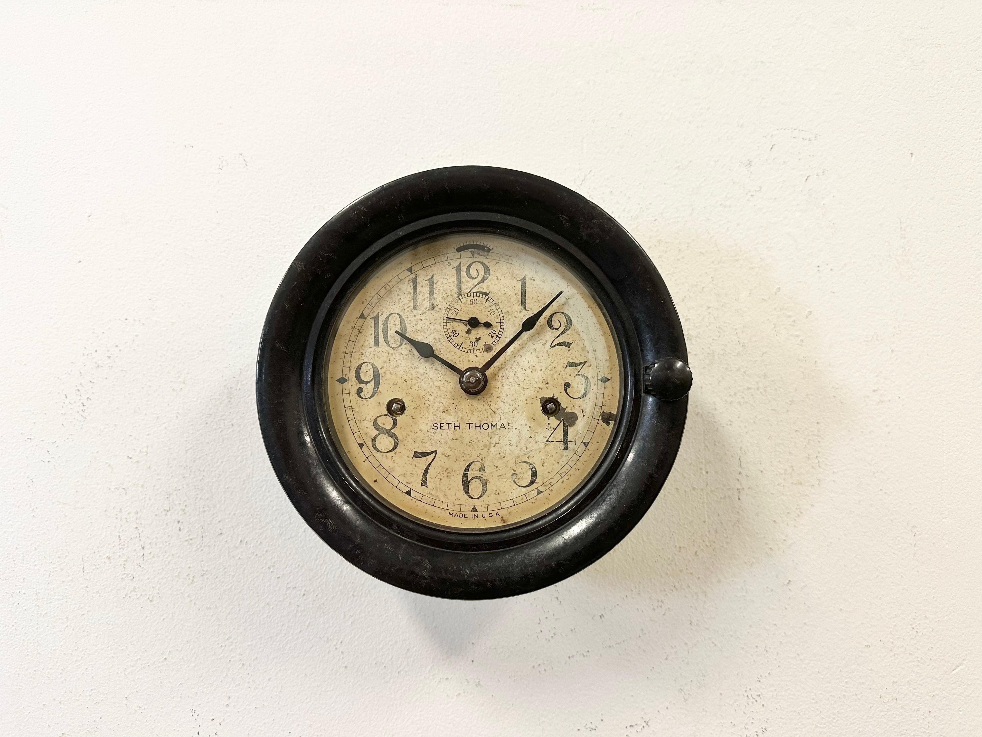 Horloge murale vintage en bakélite pour bateaux, fabriquée par Seth Thomas Clock Company aux Etats-Unis dans les années 1950, avec un boîtier en bakélite marron foncé et un couvercle en verre transparent. Le mouvement mécanique d'origine fonctionne