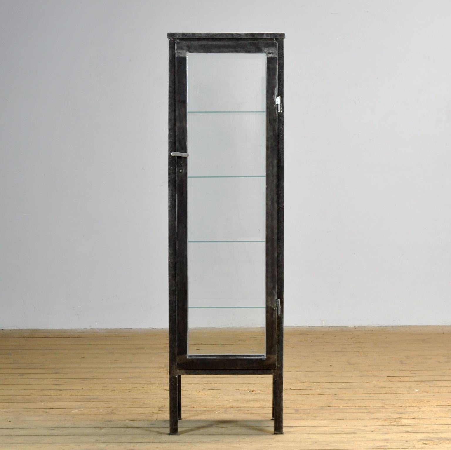 Cabinet médical en fer et en verre. Le meuble date des années 1930 et a été fabriqué en Hongrie. L'armoire est dépouillée jusqu'au métal et finie avec une laque transparente. Livré avec 4 étagères en verre. Cette armoire est vitrée sur ses quatre