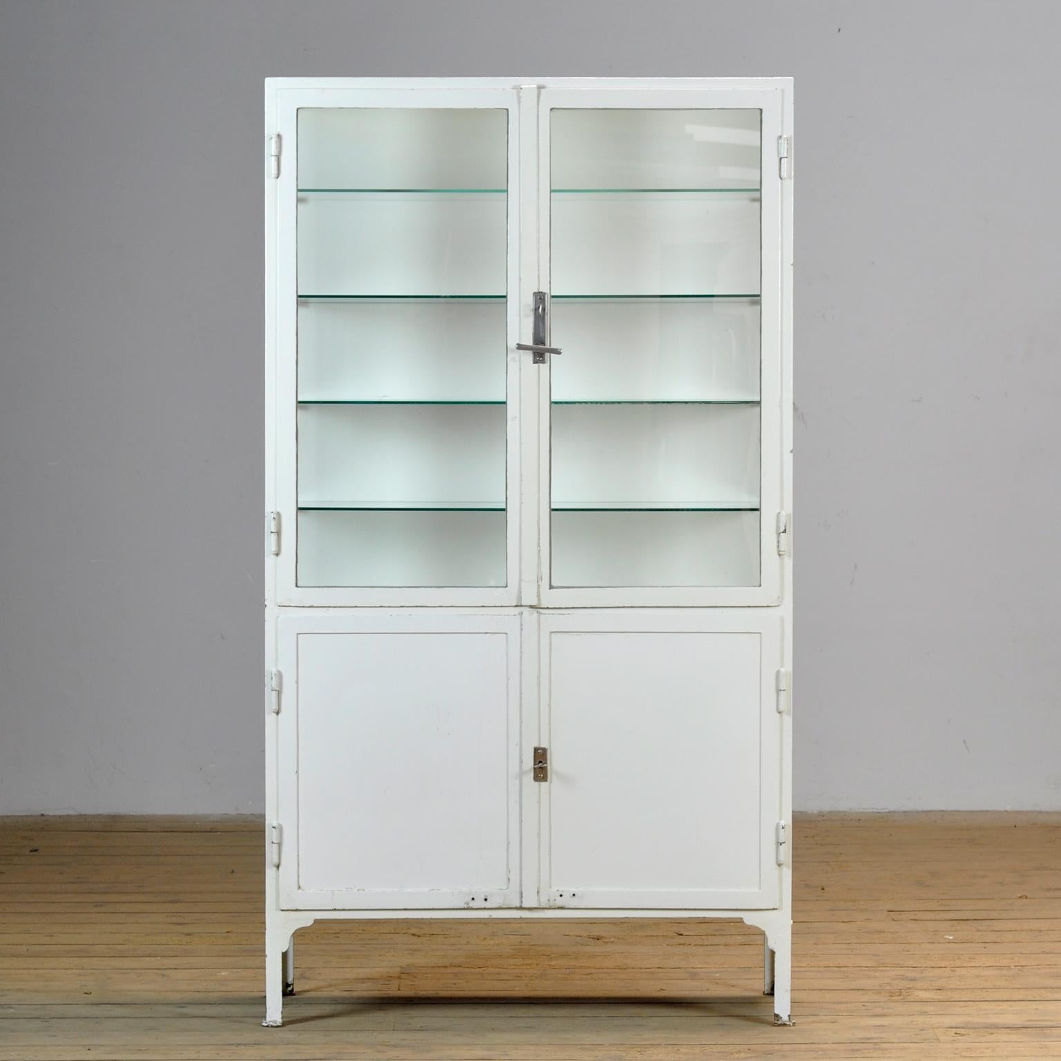 Cabinet médical des années 1930. L'armoire est fabriquée en Hongrie et est composée de fer épais et de verre. L'armoire est dotée de son verre antique d'origine. Les étagères en verre sont neuves. De qualité supérieure, l'armoire pèse environ 80 kg.