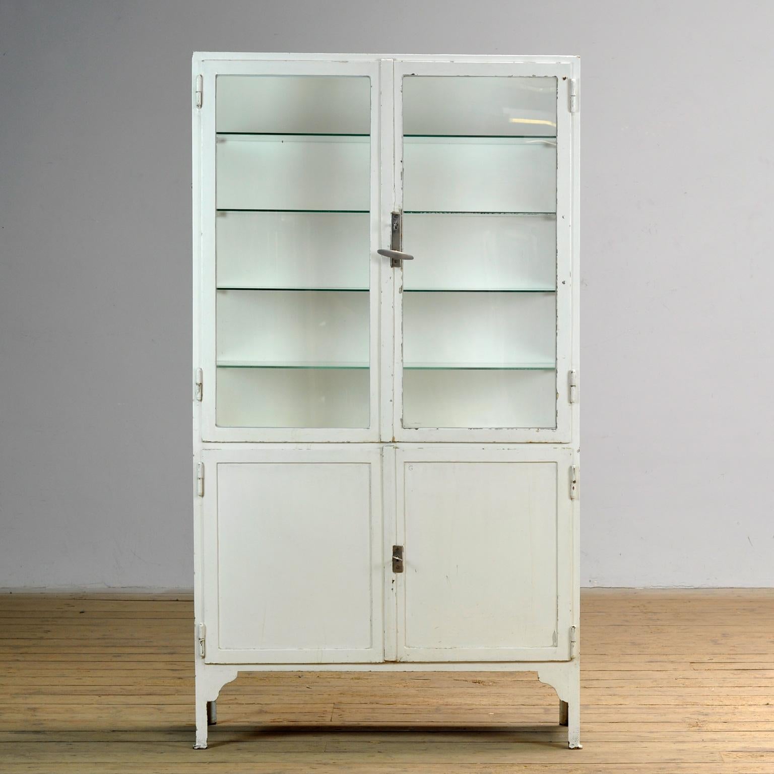 Medical cabinet from the 1930s. The cabinet is produced in Hungary and is made of thick iron and glass. The cabinet has its original antique glass. The glass shelves are new. Heavy quality, the cabinet weighs approximately 80kg.