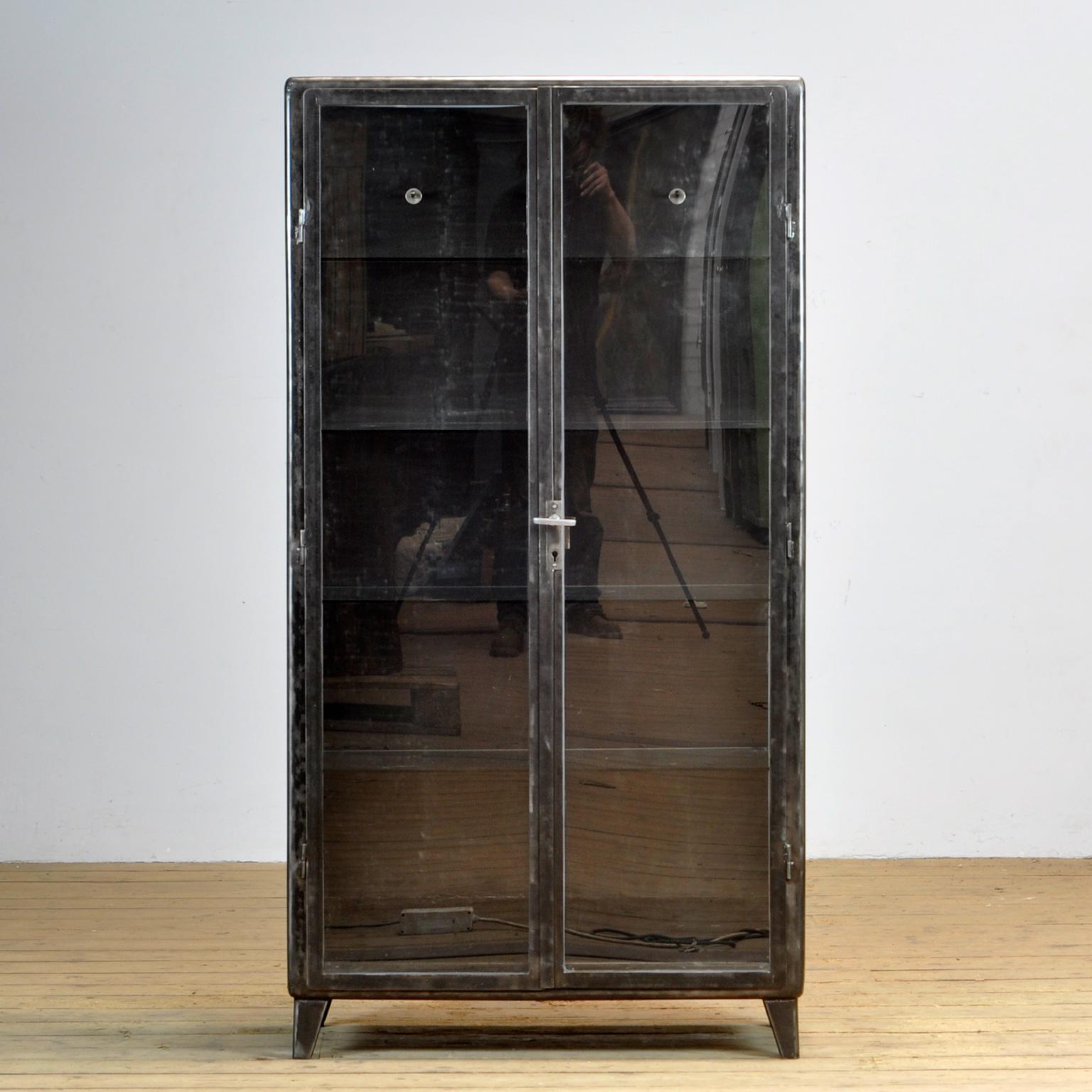 Polish medical cabinet, produced in the 1960’s. Made of iron and glass. Elegant design with rounded corners. On the inside three clothes hooks and 4 glass shelves. The cabinet has been stripped to the metal and finished with a transparent lacquer.