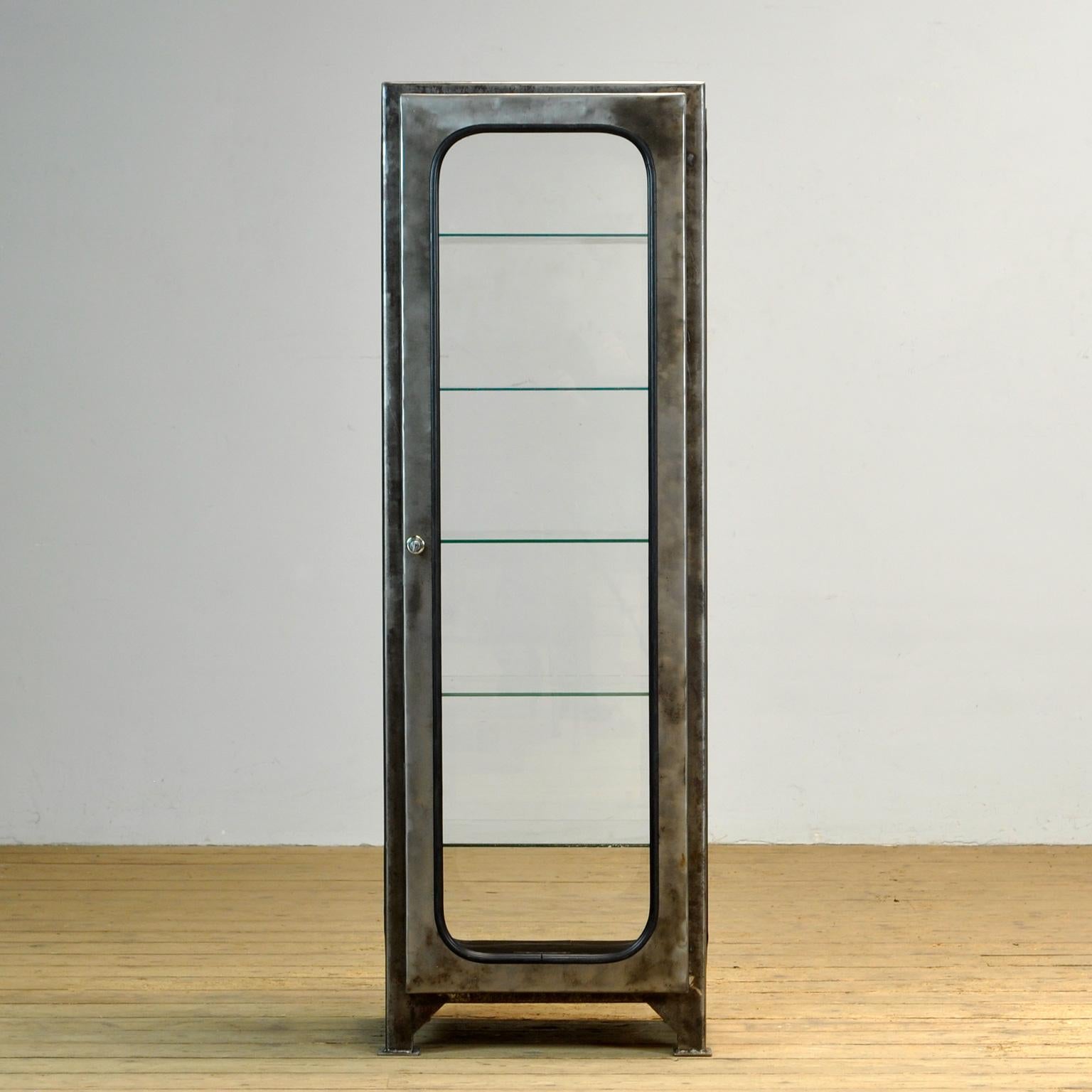 Made of steel and glass that is clamped in the steel by a rubber strip. The cabinet is from the 1970s and was produced in Hungary. The showcase has been stripped to the metal and finished with a transparent lacquer. Comes with 5 glass (adjustable)