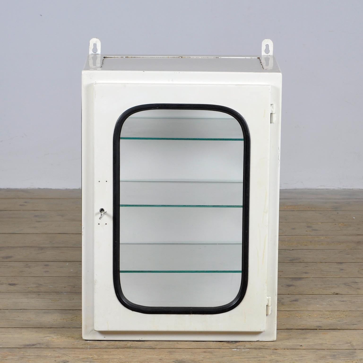 Armoire médicale (unité murale) provenant d'un hôpital. Fabriqué en fer et en verre qui est serré dans l'acier par une bande de caoutchouc. Cette armoire date des années 1970 et a été fabriquée en Hongrie. Avec 3 étagères en verre réglables.