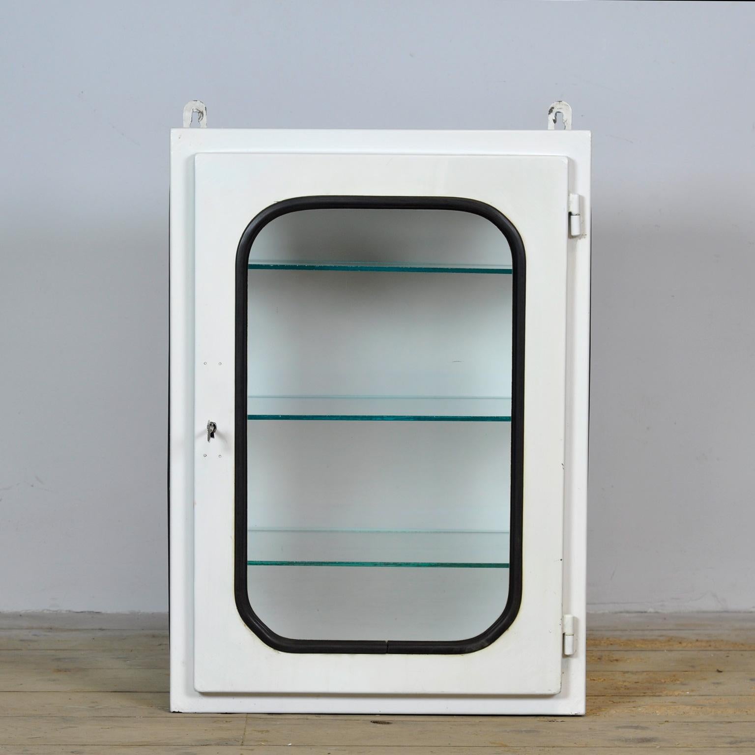 Armoire médicale (unité murale) provenant d'un hôpital. Fabriqué en fer et en verre qui est serré dans l'acier par une bande de caoutchouc. Cette armoire date des années 1970 et a été fabriquée en Hongrie. Avec 3 étagères en verre réglables.