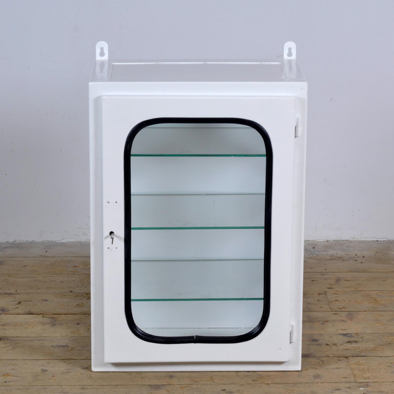 Armoire à pharmacie (unité murale) provenant d'un hôpital. Fabriqué en fer et en verre qui est serré dans l'acier par une bande de caoutchouc. Cette armoire date des années 70 et a été fabriquée en Hongrie. Avec 3 étagères en verre réglables.