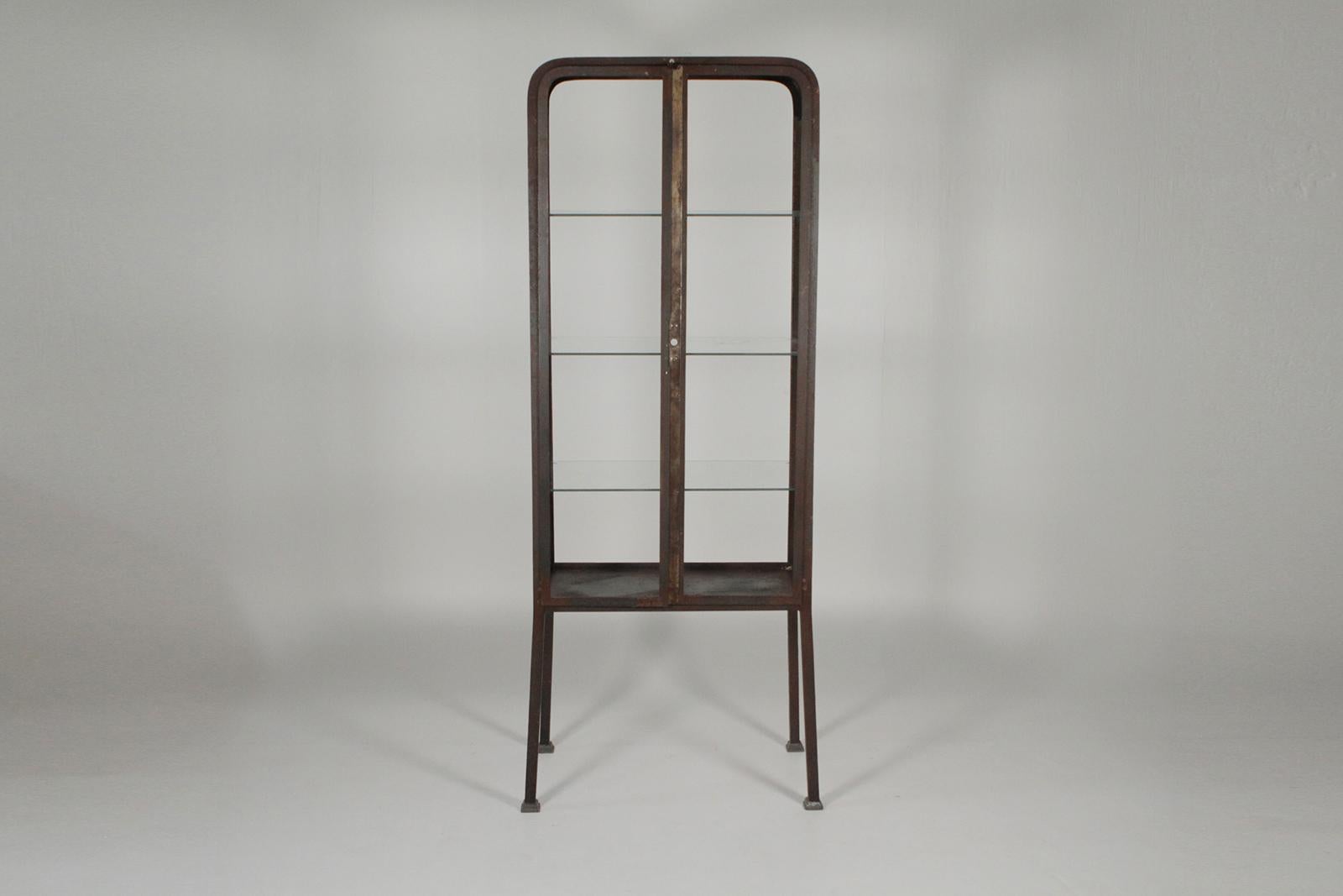 Vintage medical cabinet with a weathered rusted steel finish now as a bar. The doors are intentionally made stationary and the glass on all sides having been removed for easy access and use as a bar. Marked Buenos Aires on the underside 69