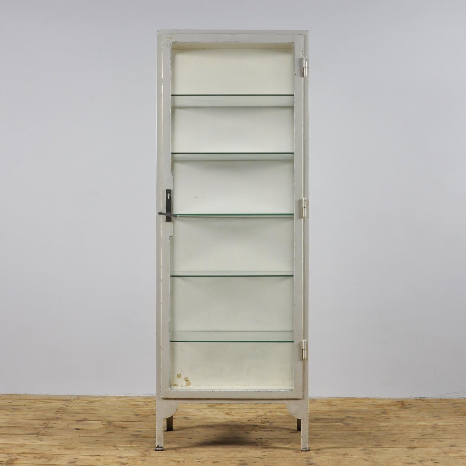 This vintage cabinet was produced in Austria during the 1940s. The cabinet is made of thick steel and comes with five glass shelves. The item has a working lock with handle and key. It is in a nice vintage condition, missing some paint in places.
 