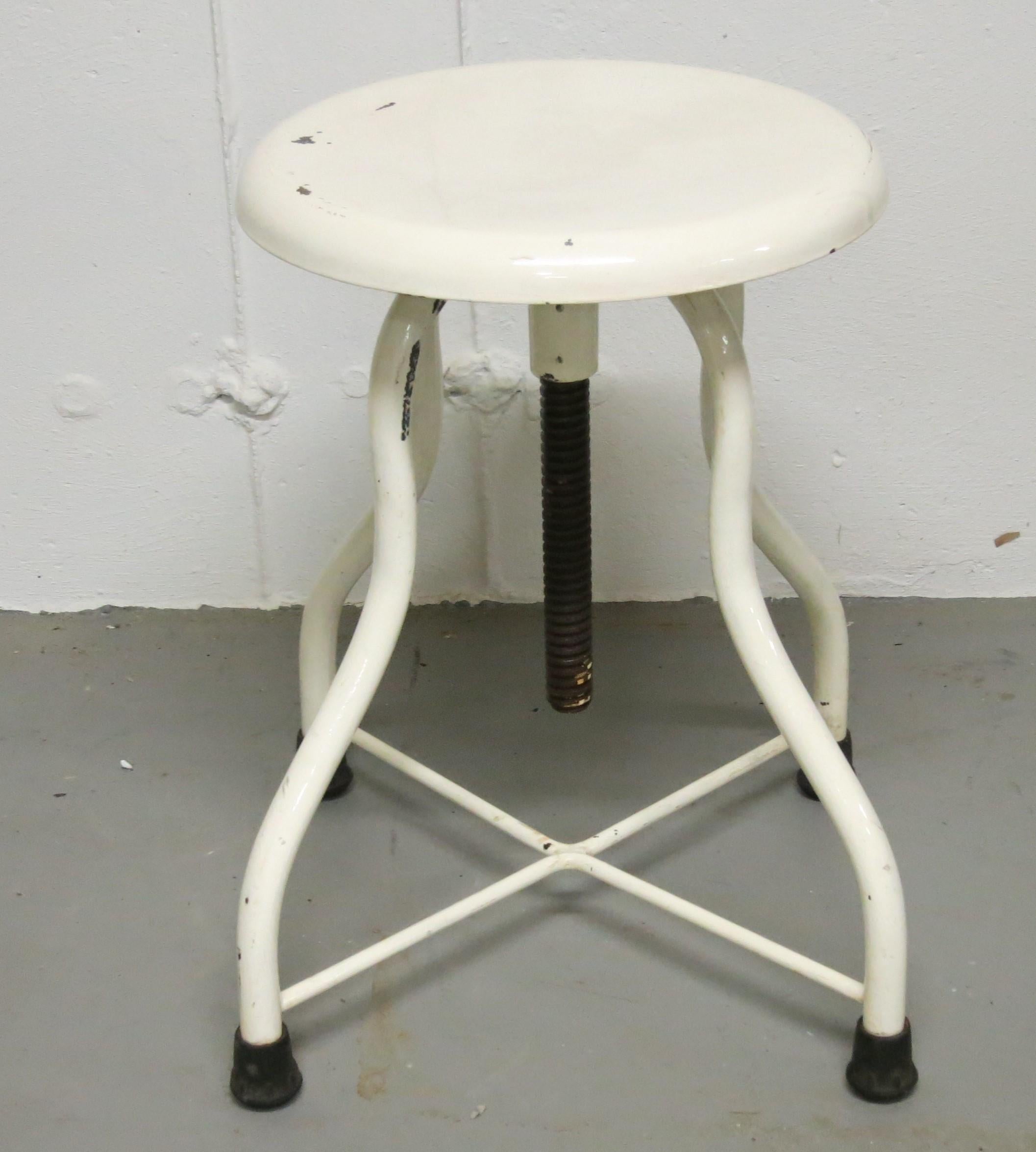 Vintage medical stool painted white with paint loss and scratches. It is 14