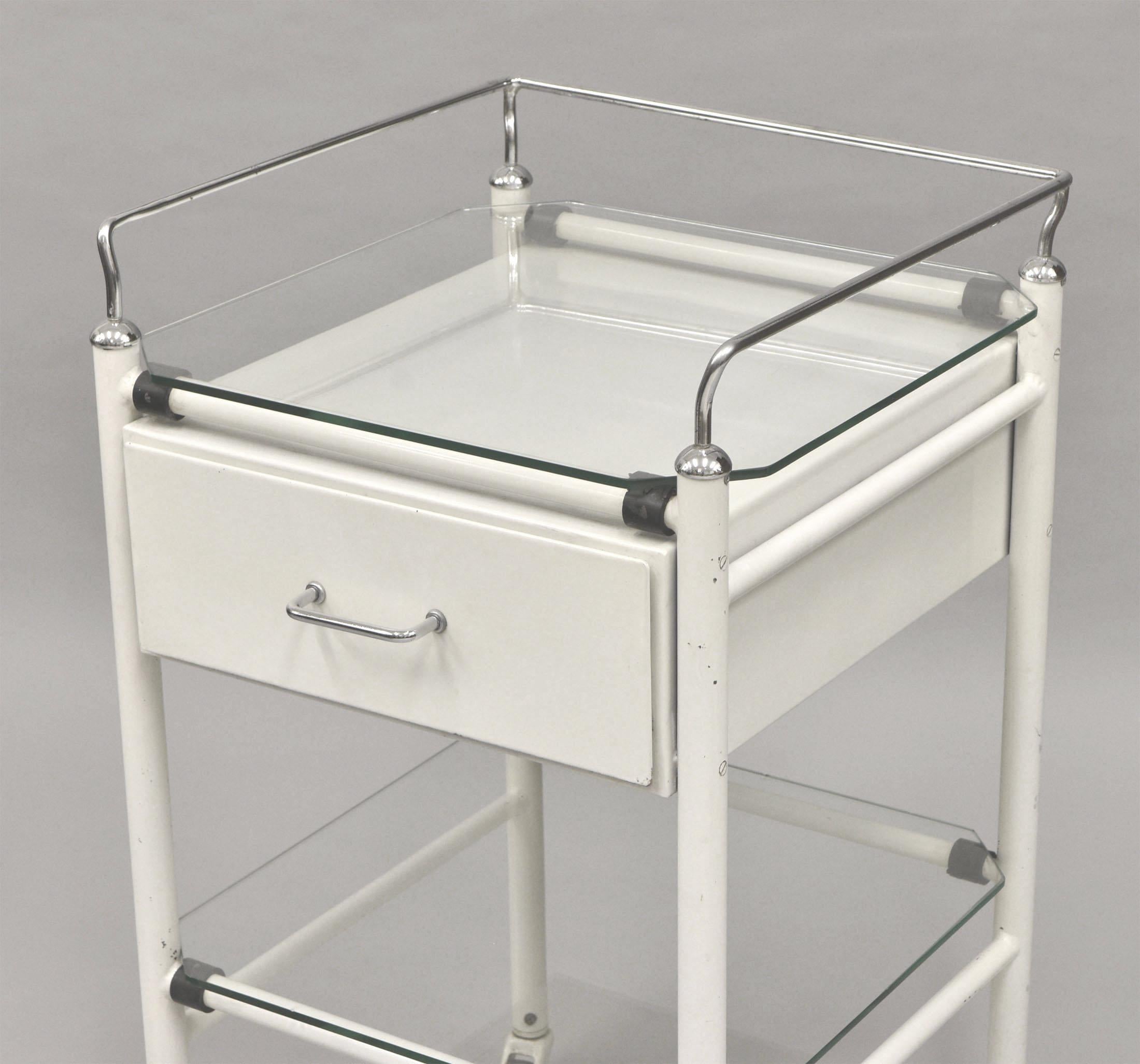 A vintage medical trolley with drawer. Circa 1950.

It has the original finish, showing some scuff marks expected with use, but generally in good condition, please refer to the photographs. The glass does have a few nicks in places, also shown in