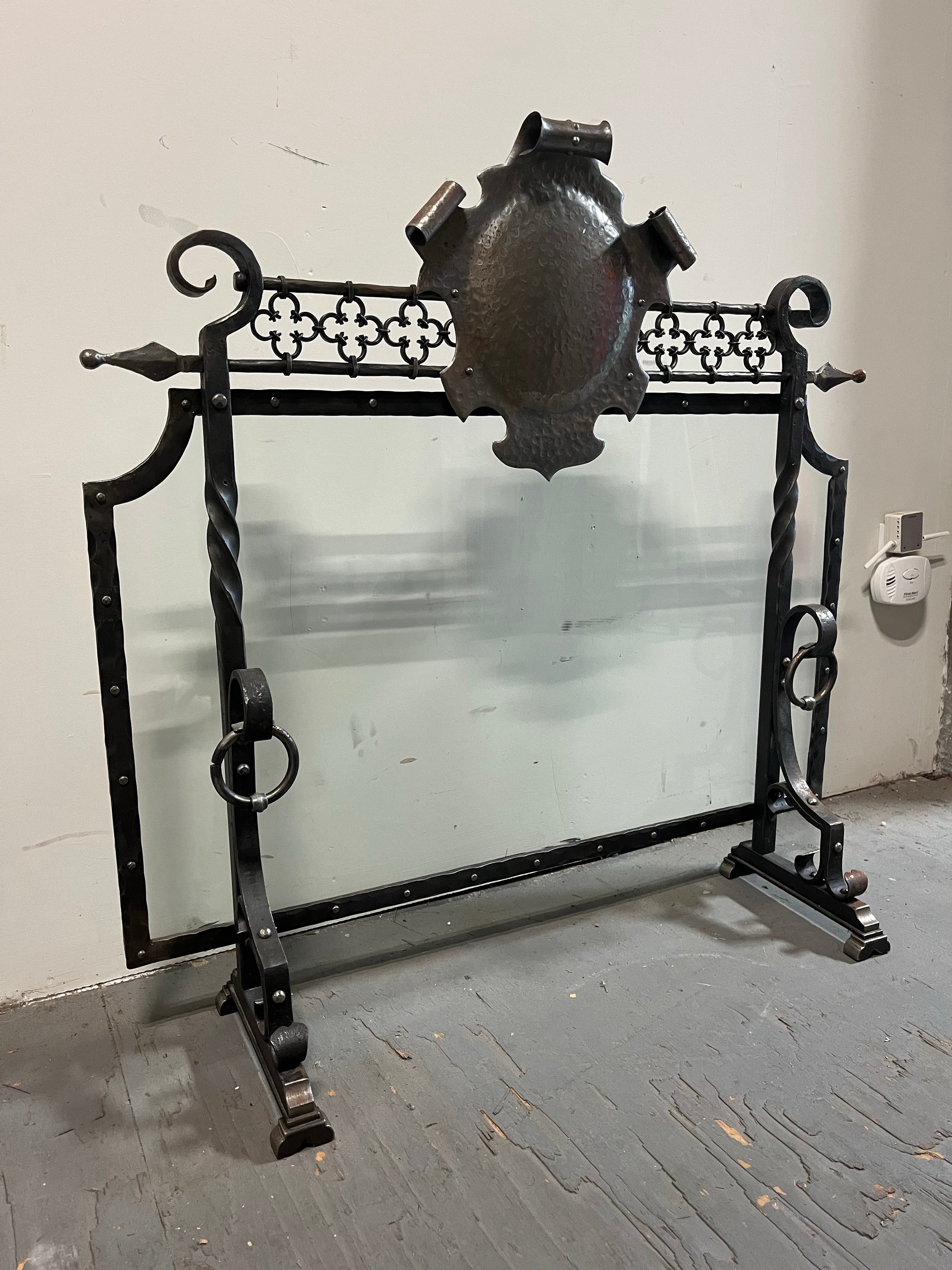 Questo parafuoco gotico medievale vintage con crest e inserto in vetro è un pezzo unico ed elegante, perfetto per aggiungere un tocco di charme storico a qualsiasi camino. Realizzato in ferro battuto di colore grigio, questo paravento vintage