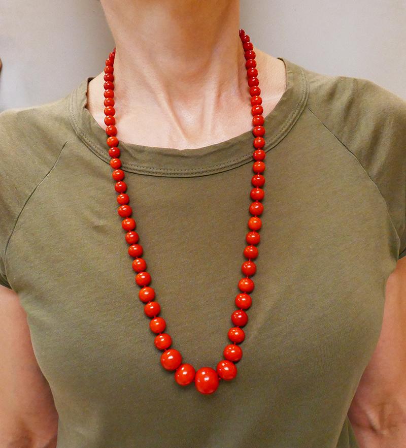 A long vintage Mediterranean coral necklace. This coral strand necklace consists of graduating size coral beads and a 14 karat white gold clasp embellished with diamonds. The central bead measures 17.9 x 15.9 mm the smallest bead is 8.0 x 6.8