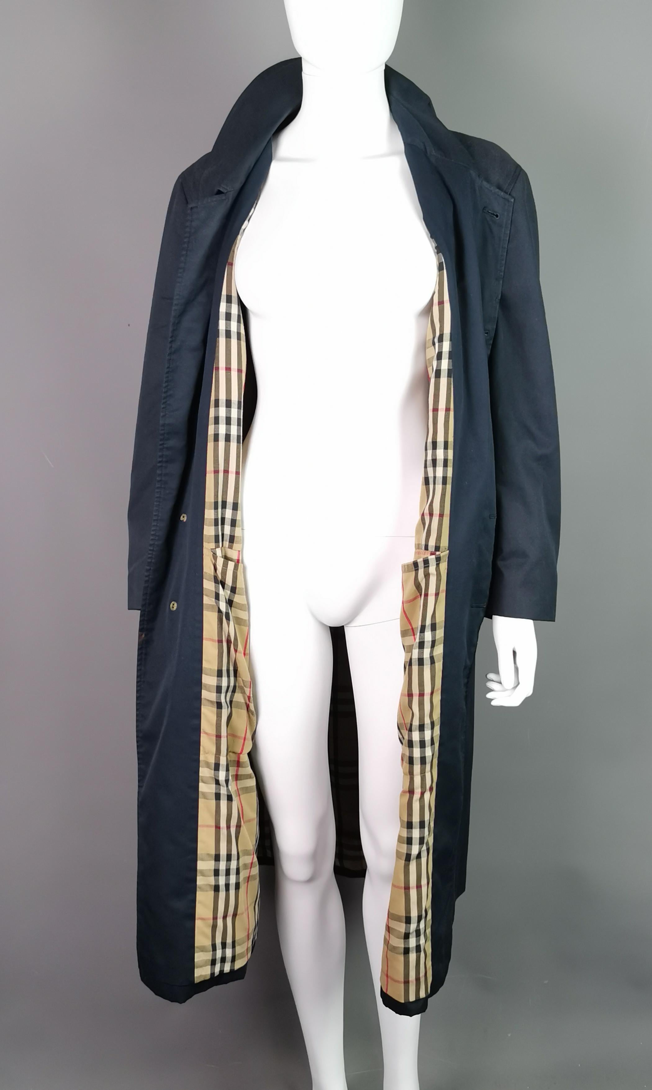 A stylish and iconic vintage Burberry mens trench coat or mac.

This is a beltless trench coat, navy blue with a classic Burberry Nova check lining.

It fastens with a concealed plastic button fastening.

Labelled Burberrys a classic and iconic