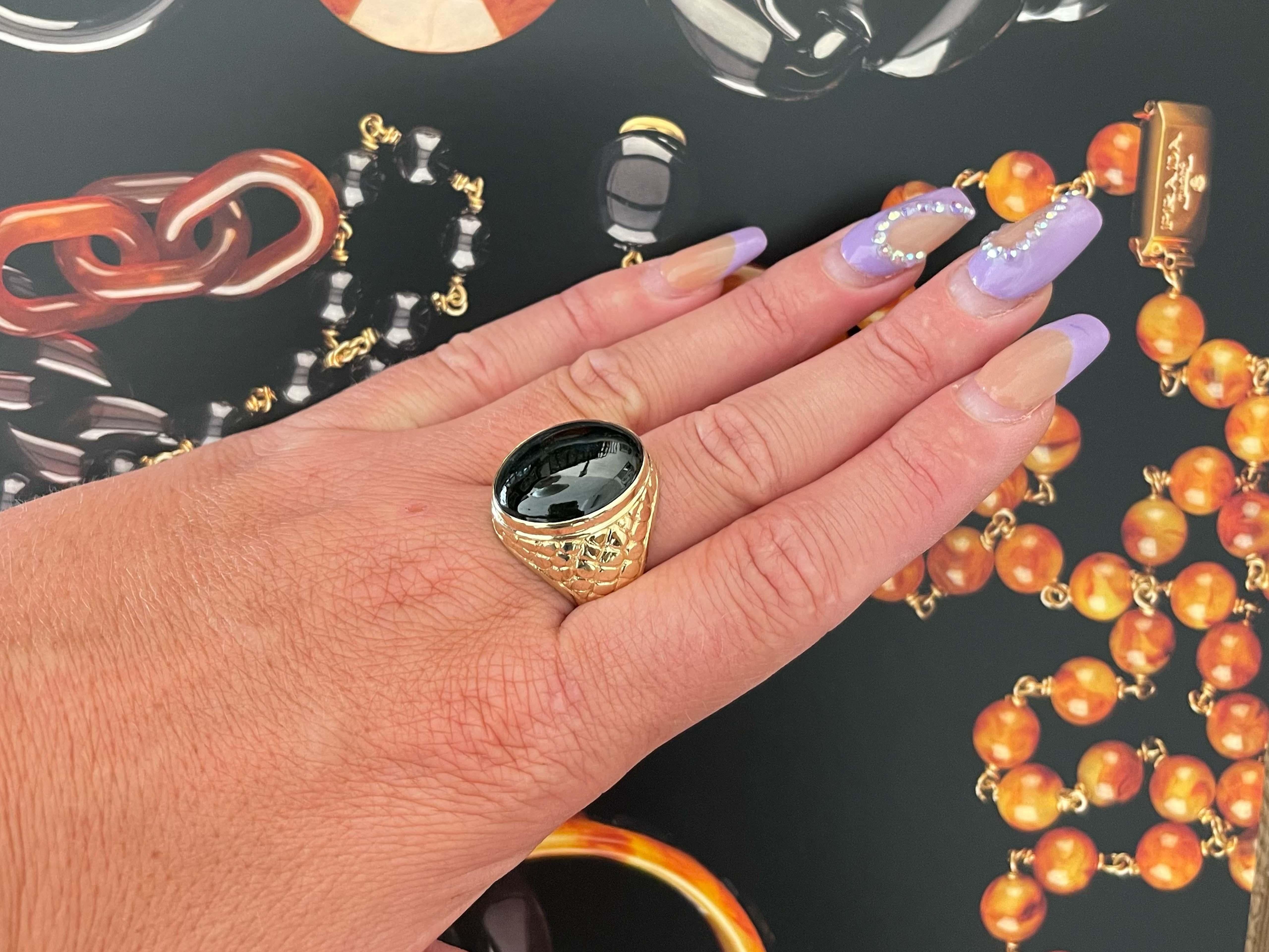 Magnificent vintage oval cabochon black jade ring in 14k yellow gold. The stunning black Jade is bezel set and measures approximately 20.45 mm x 15.52 mm x 7.38 mm. The ring has a tapered shank with a high polish finish and a reptile design on both