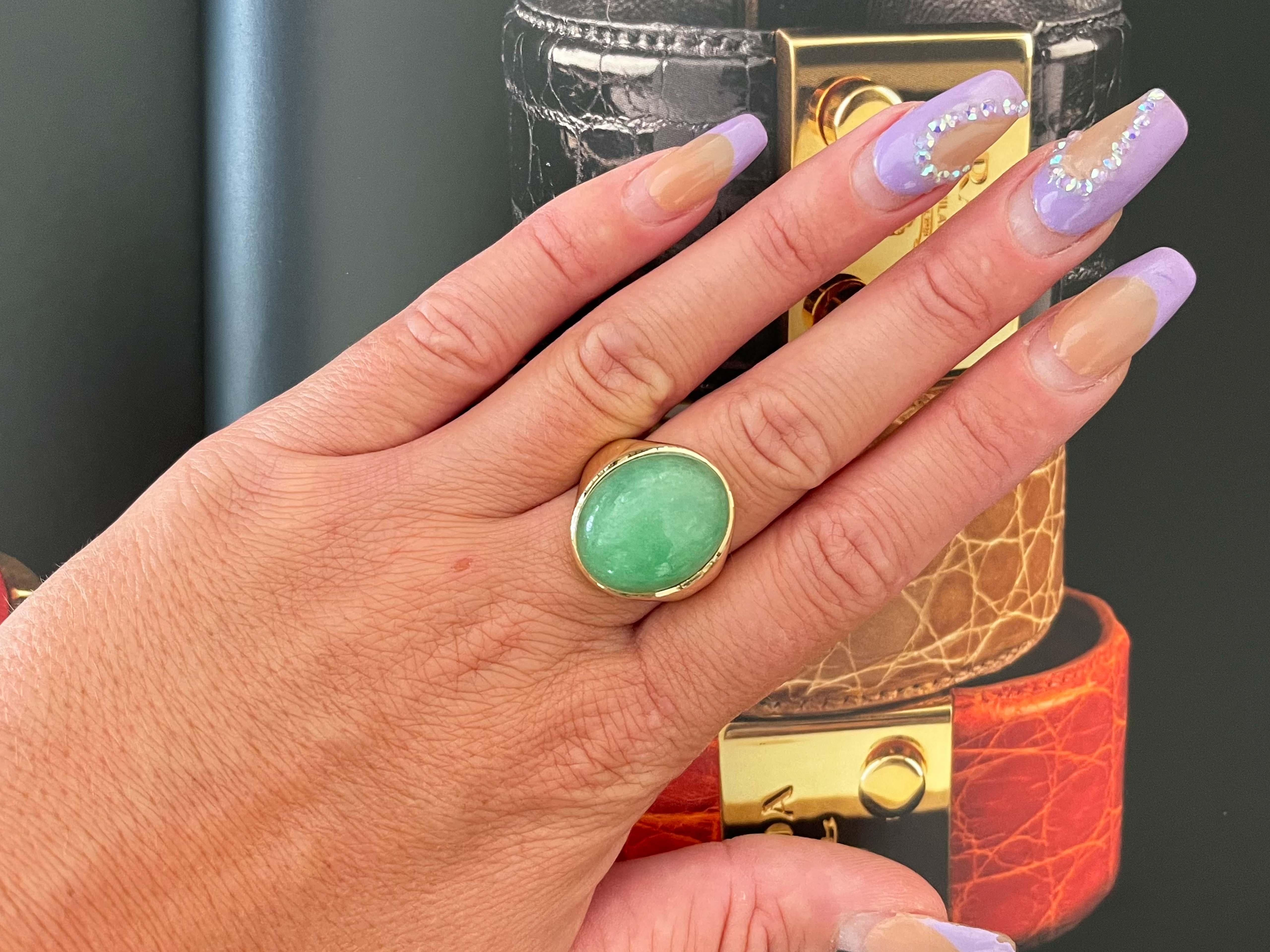 Magnificent vintage large oval cabochon green jadeite jade ring, in 14k yellow gold. The beautiful apple green Jade is bezel set and measures approximately 20.52 mm x 17.02 mm x 9.85 mm. The ring has a tapered shank with a high polish finish. The